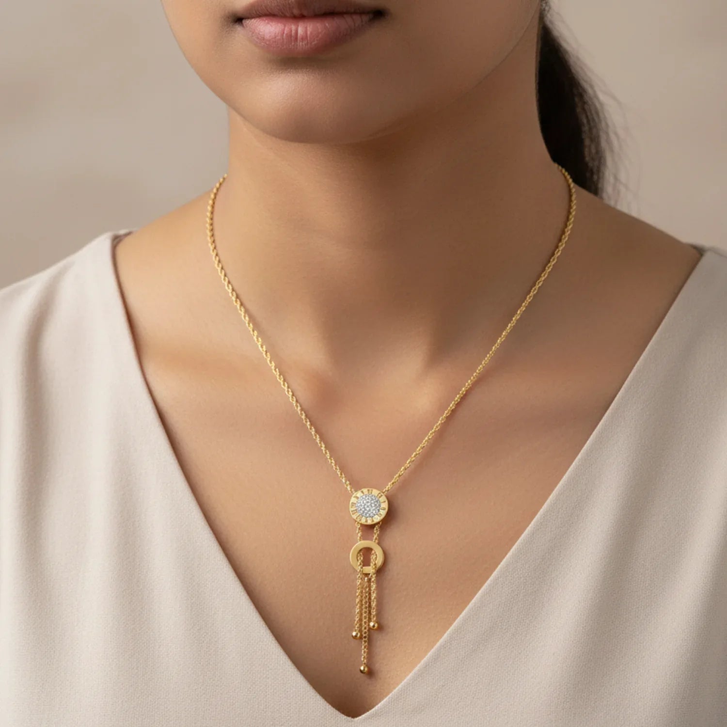 Gold necklace with a pendant worn by a person against a neutral background