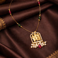 Gold necklace with a detailed pendant on a brown fabric background