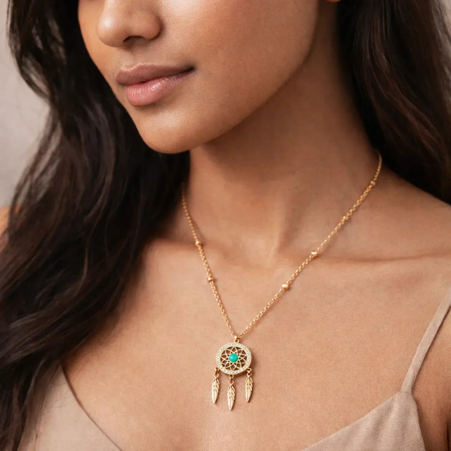 Woman wearing a gold necklace with a dreamcatcher pendant