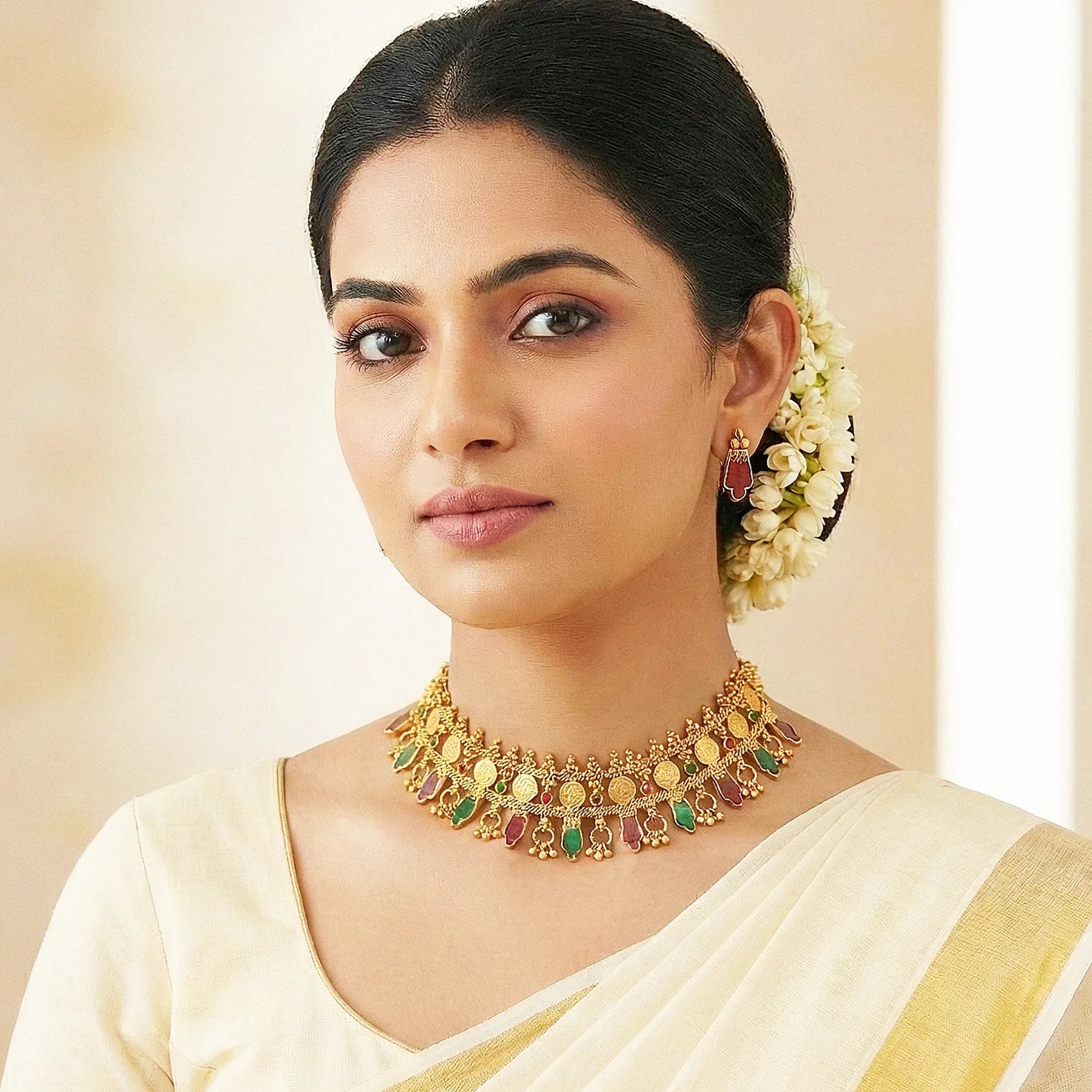 Woman wearing a gold necklace with colorful stones on a beige background