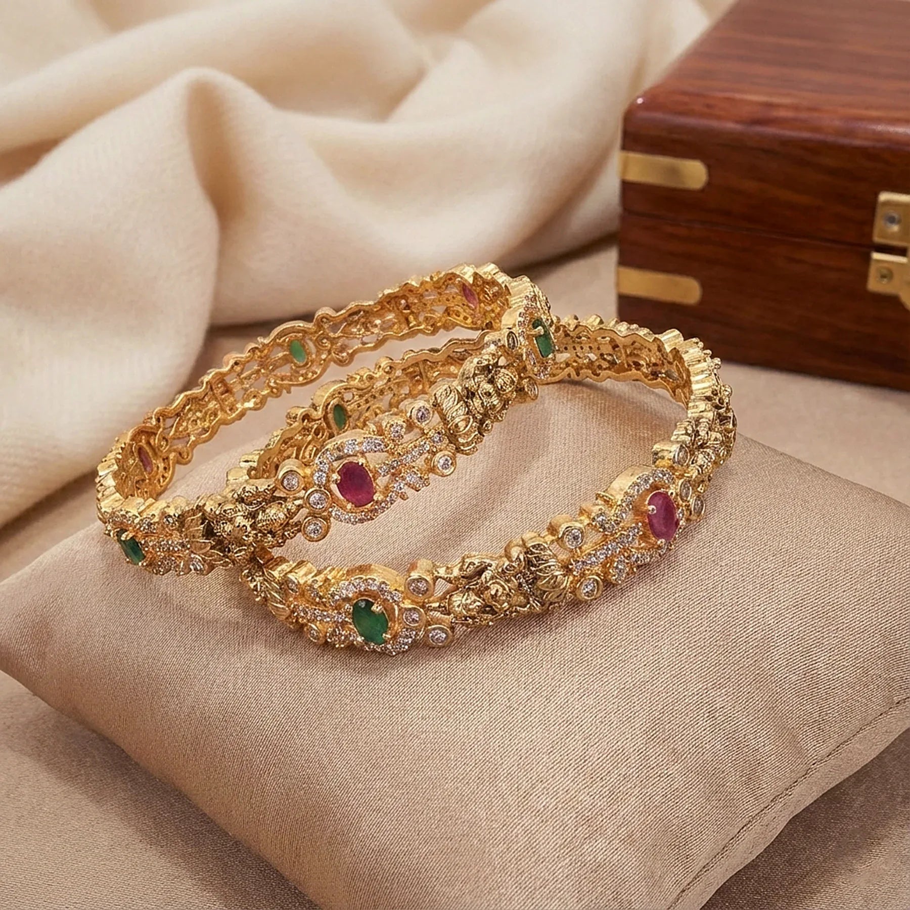 Gold bracelets with gemstones on a beige fabric background