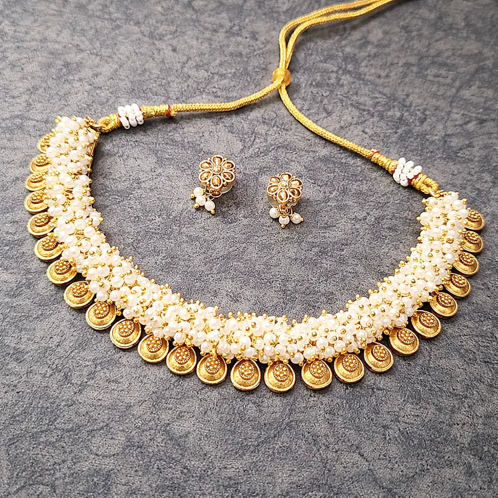 Gold and pearl necklace with matching earrings on a gray textured background