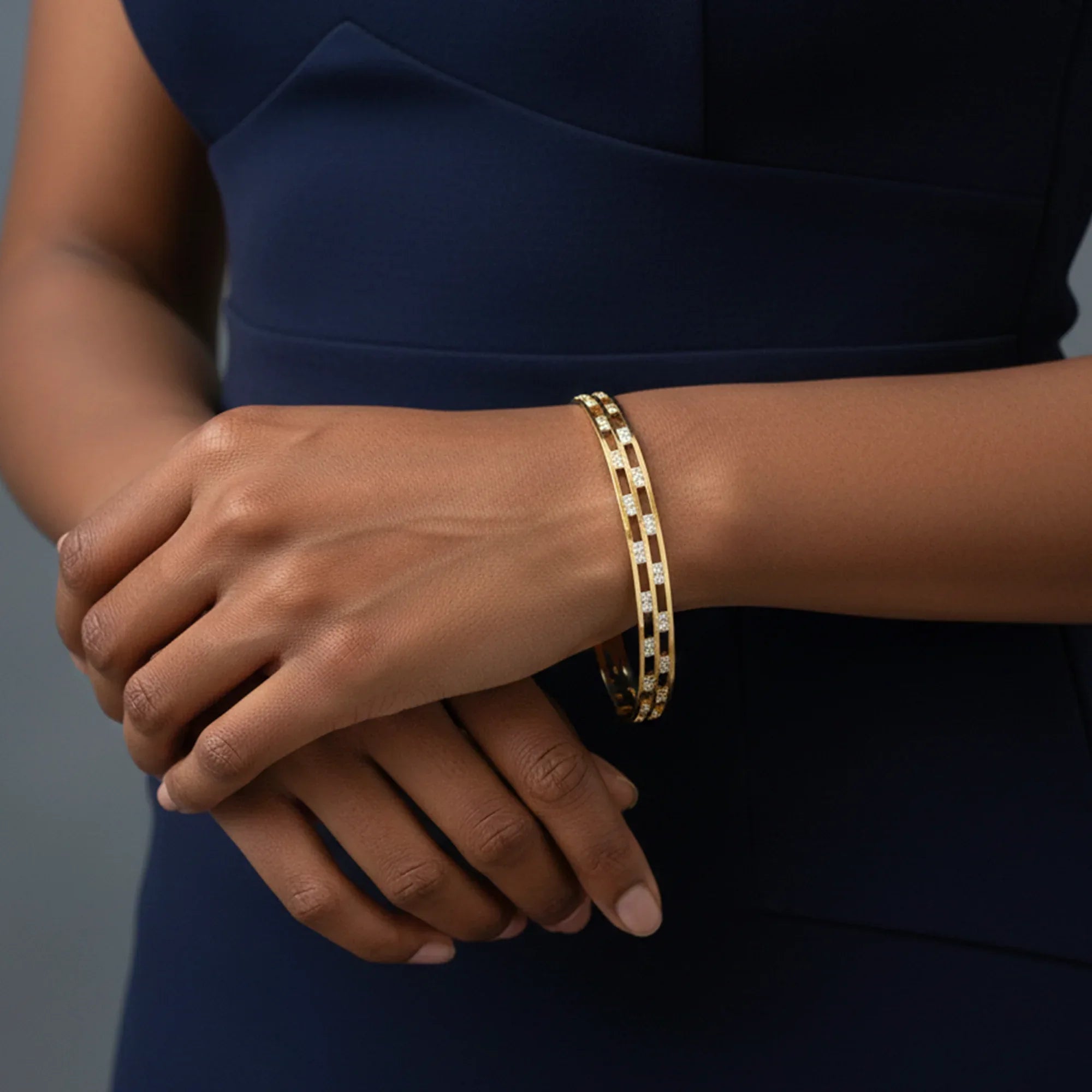 Close-up of a person wearing a gold bracelet on a dark background