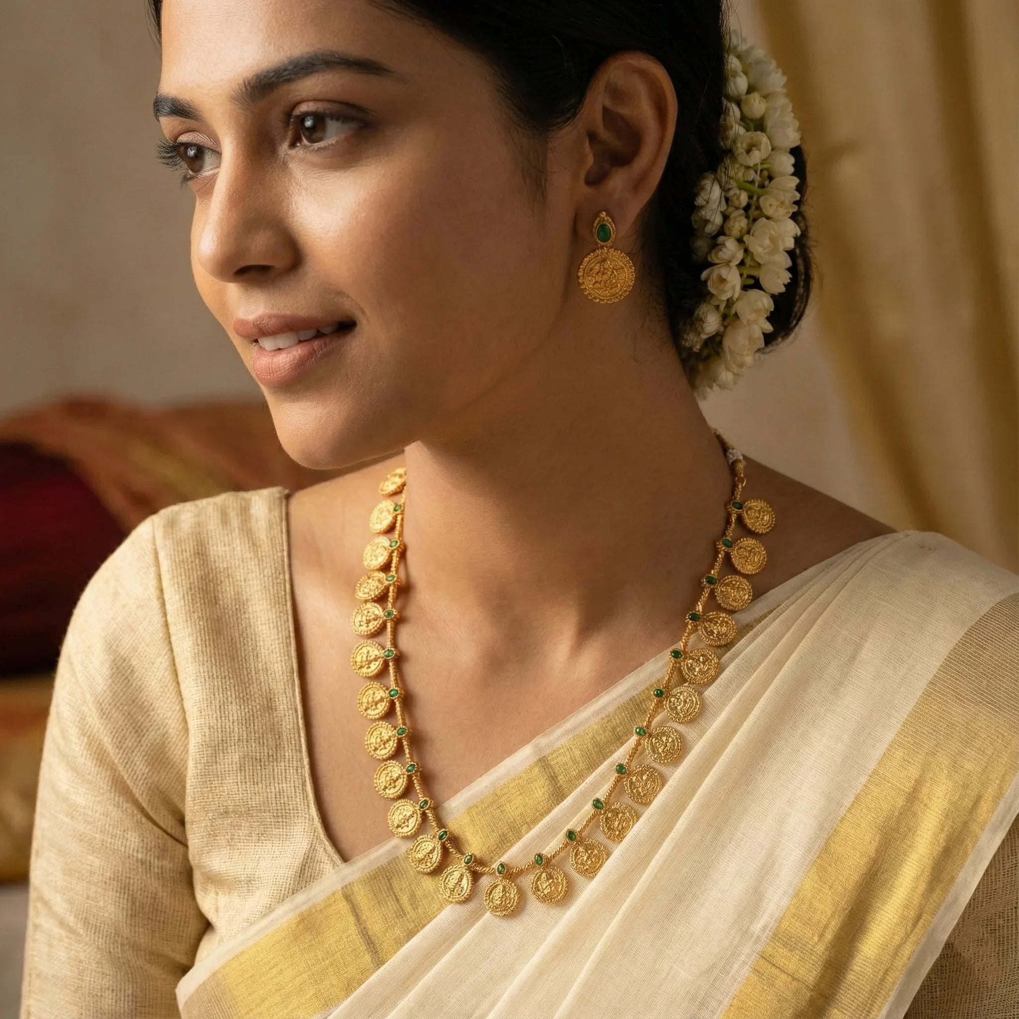 Woman wearing gold jewelry and a saree with a neutral background