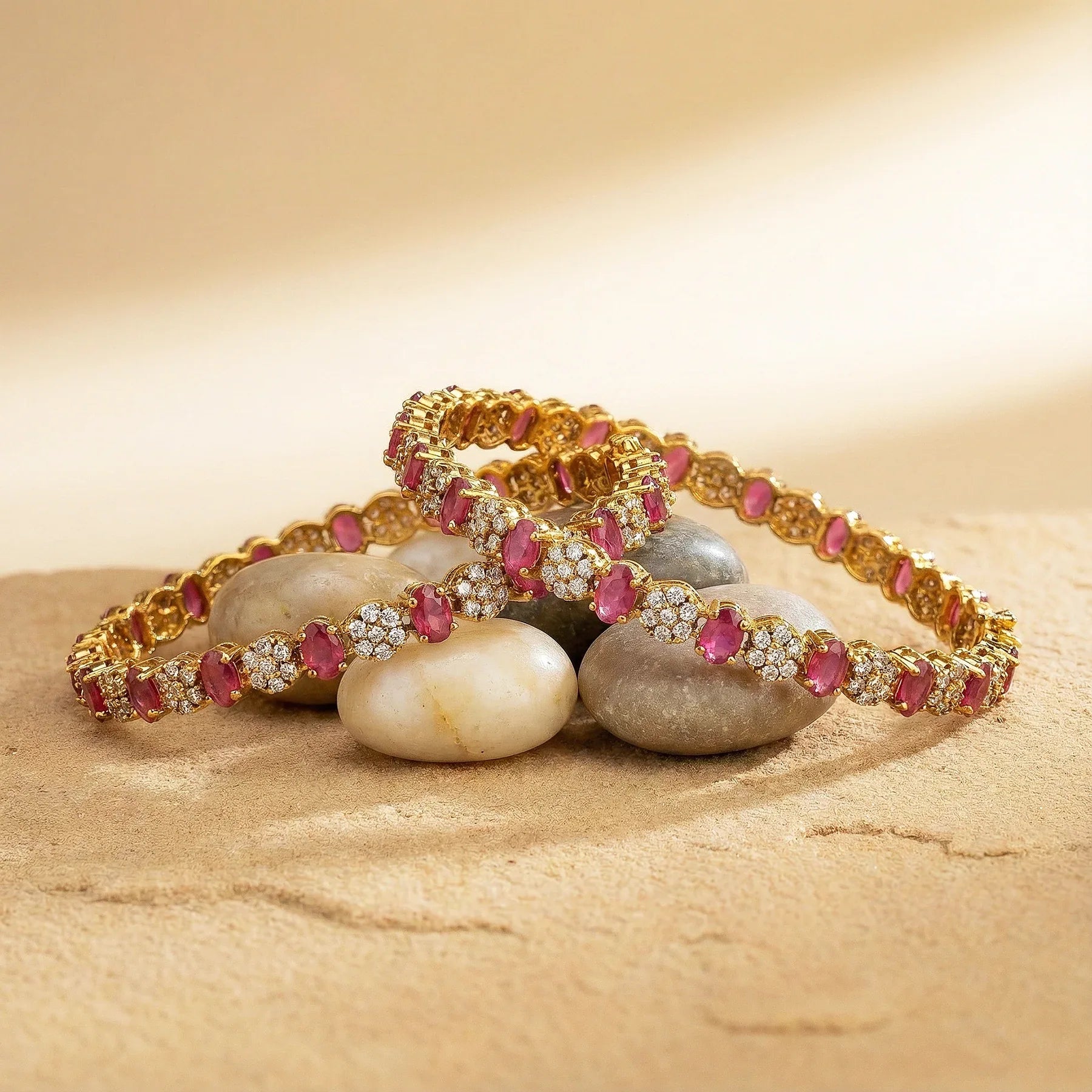 Gold bracelet with red gemstones on stones against a beige background