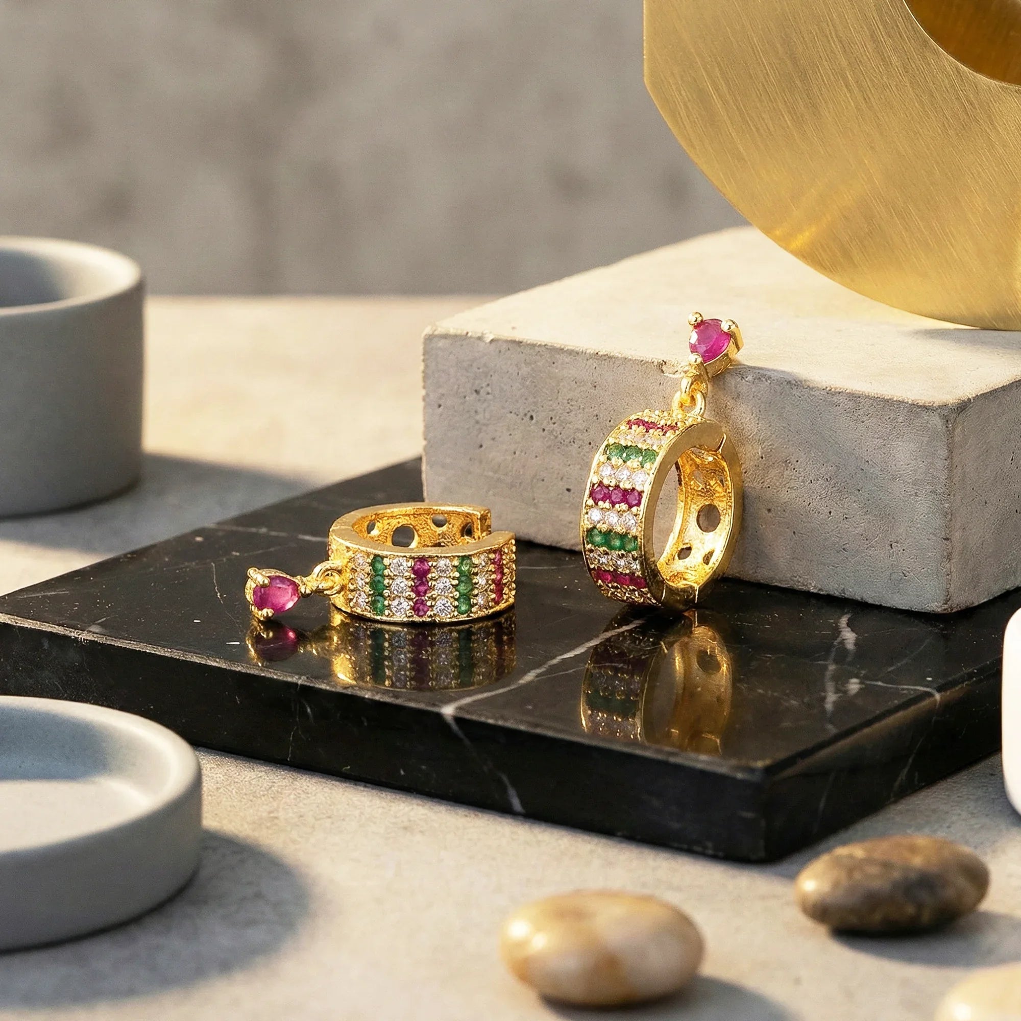 Gold earrings with gemstones on a black marble surface
