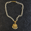 Pearl necklace with a gold pendant on a dark textured background