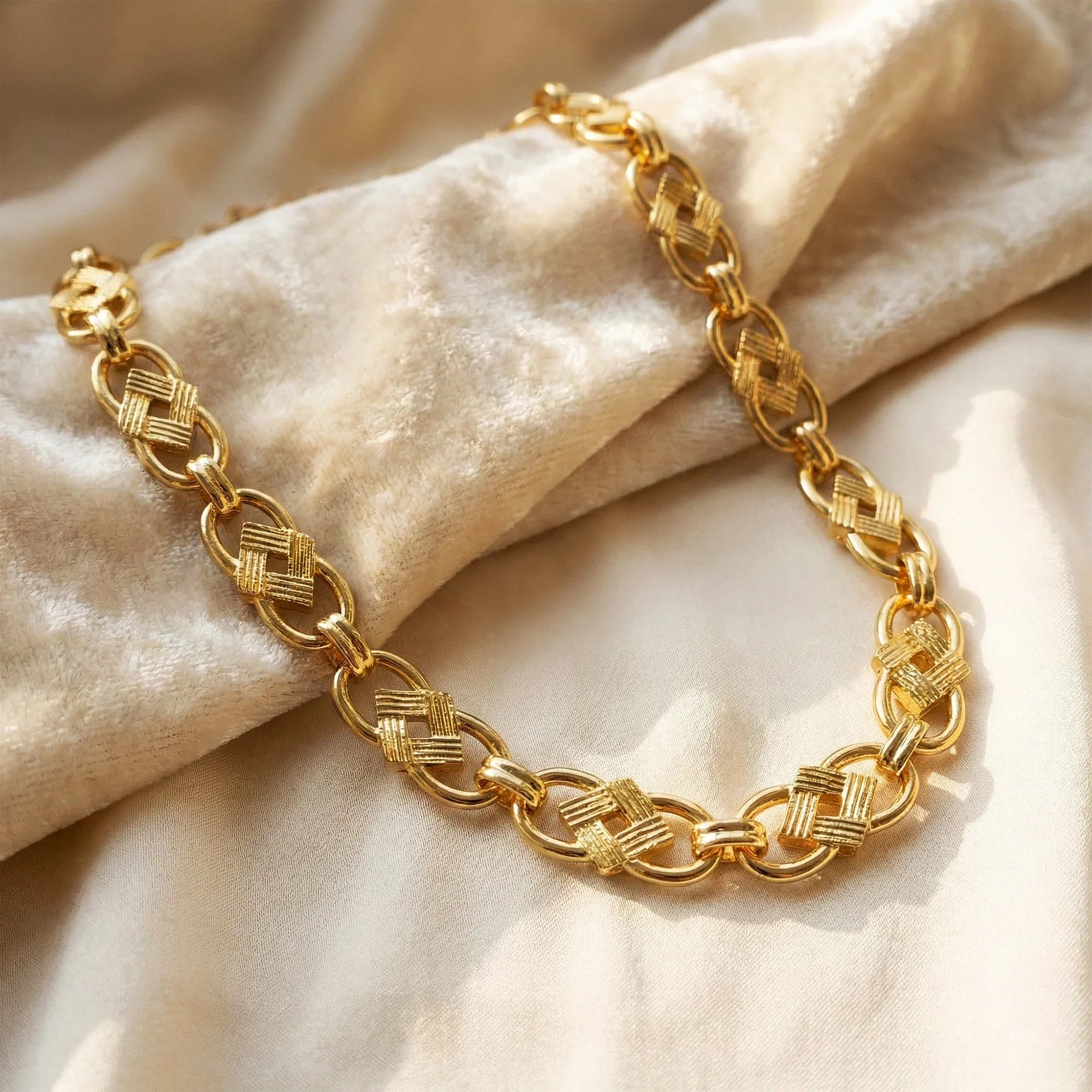 Gold chain necklace on a beige fabric background