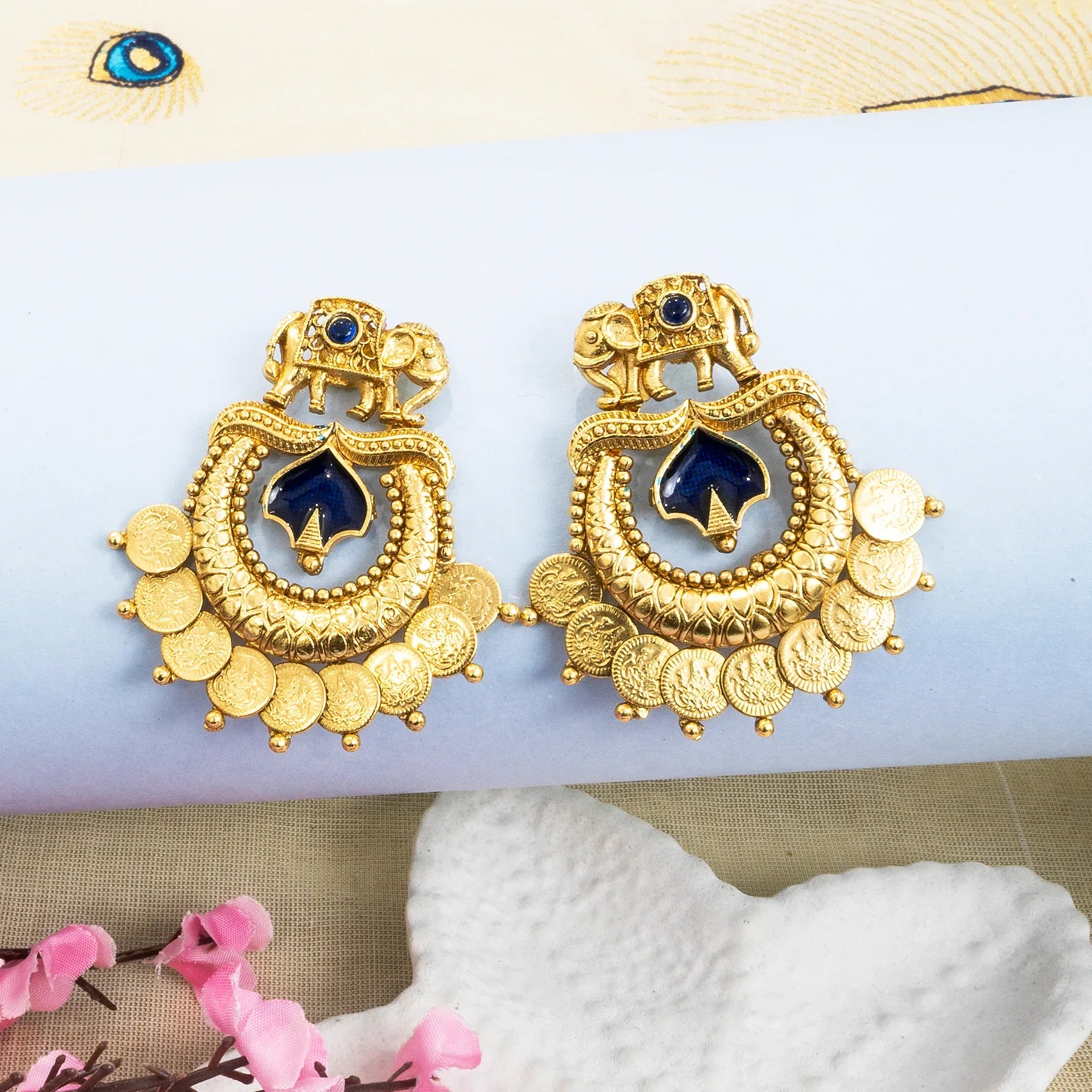 Gold earrings with blue center on a white background
