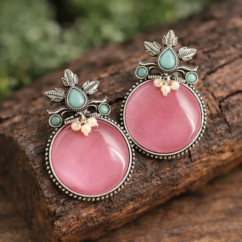 Pink earrings with gemstone accents on a wooden surface