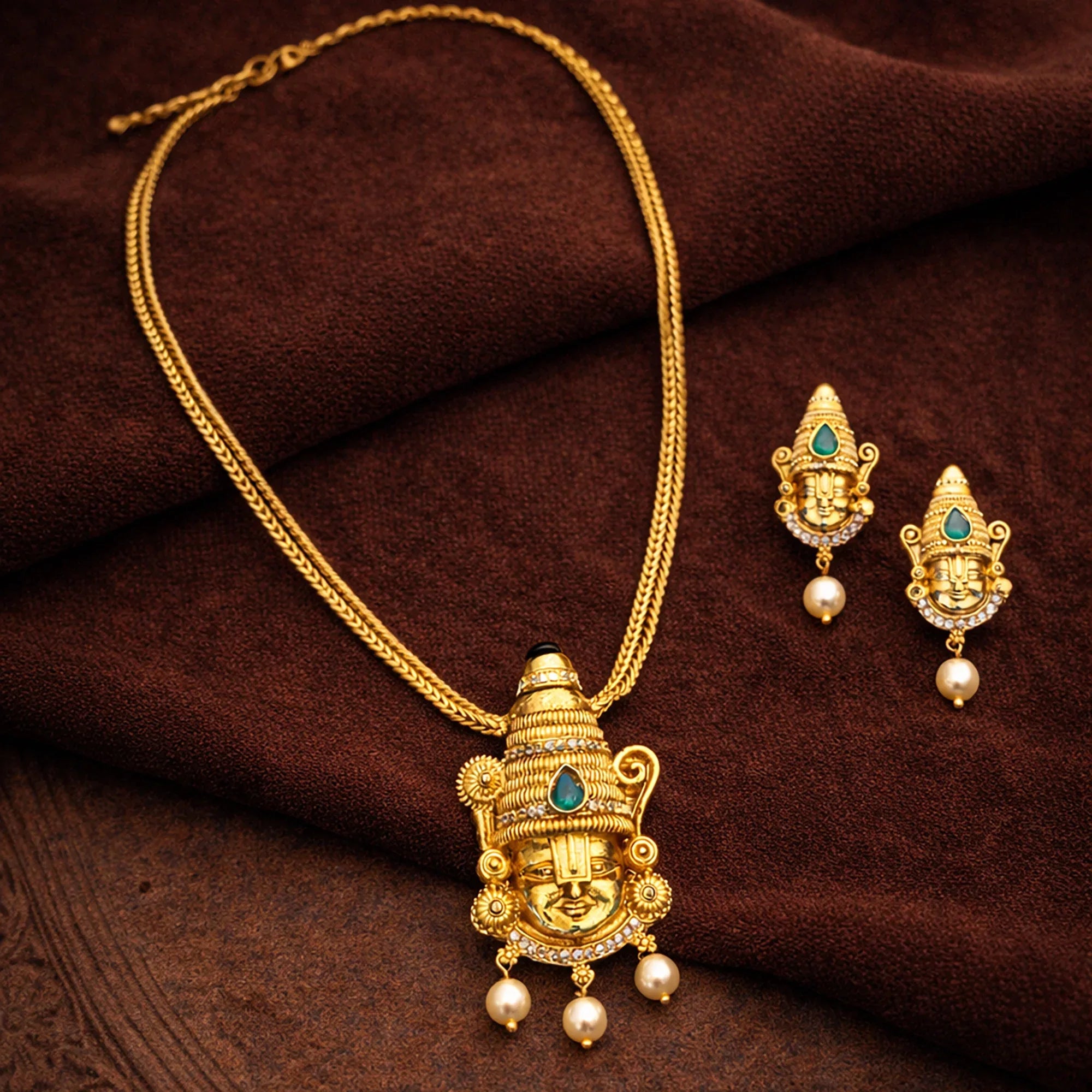 Gold necklace and earrings on a brown fabric background