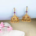 Gold earrings with purple gemstones on a light background