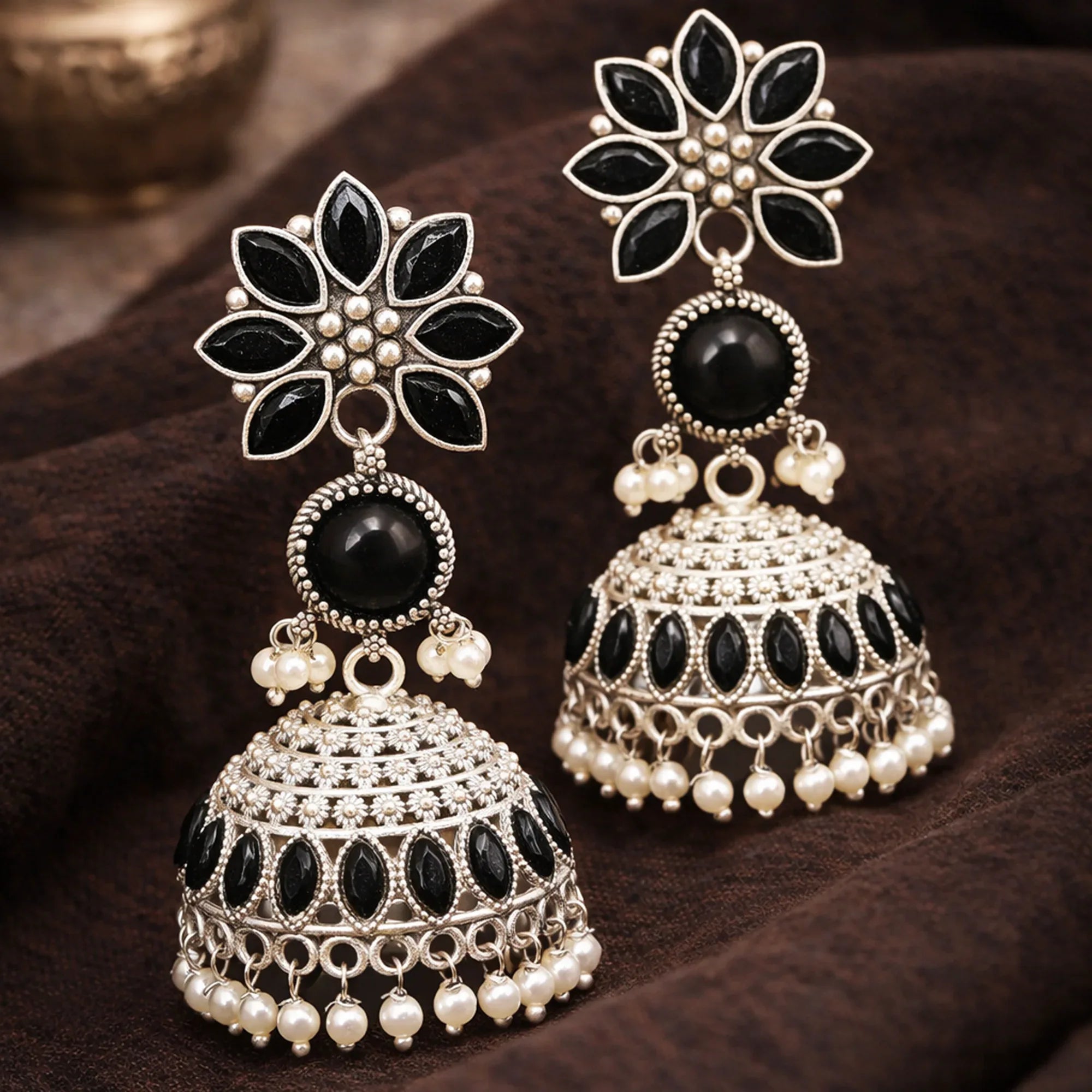 Ornate earrings with black and white stones on a brown surface