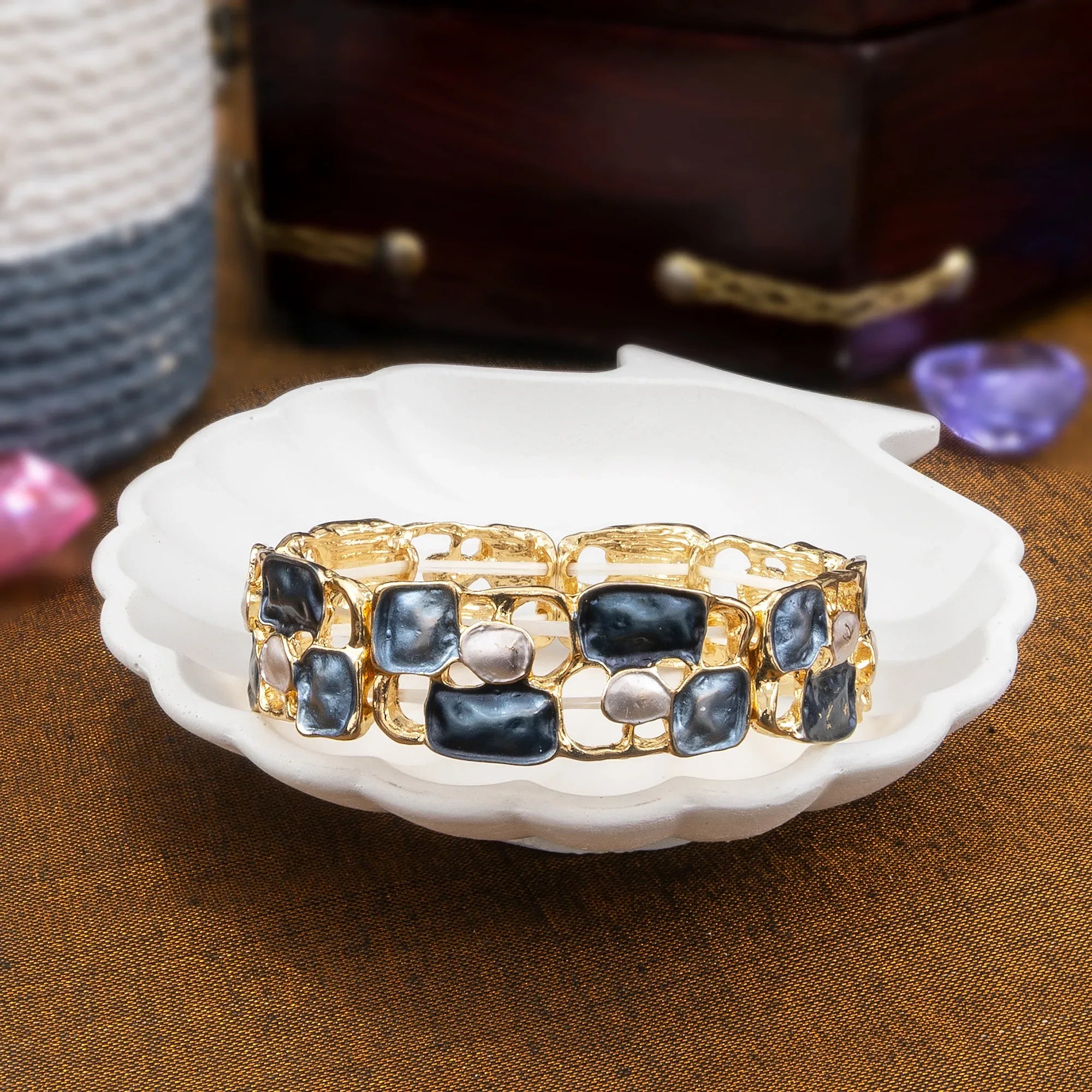 Gold and black patterned bracelet on a white dish with a brown background
