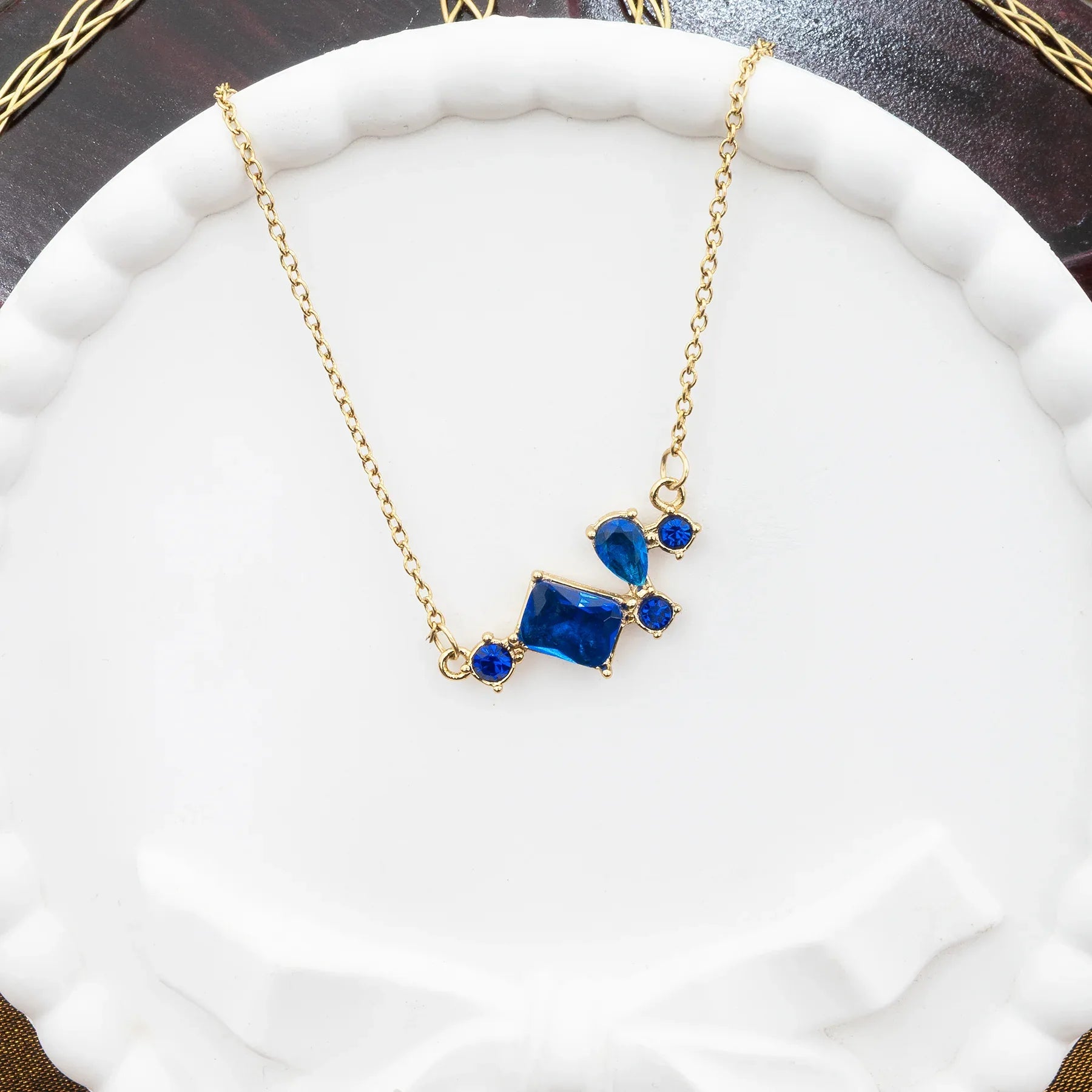 Gold necklace with blue gemstones on a white surface