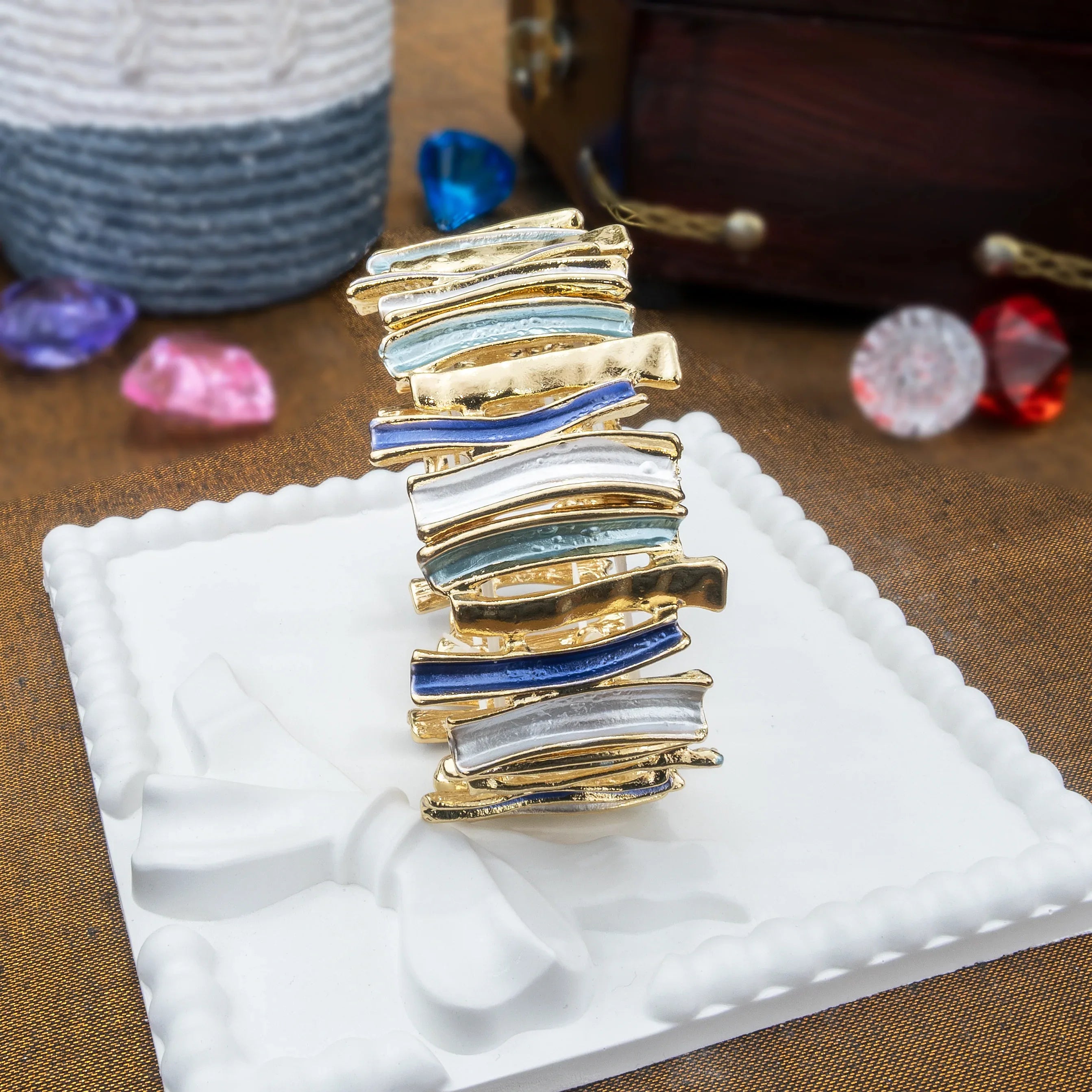 Multicolored bracelet on a white cushion with colorful stones in the background