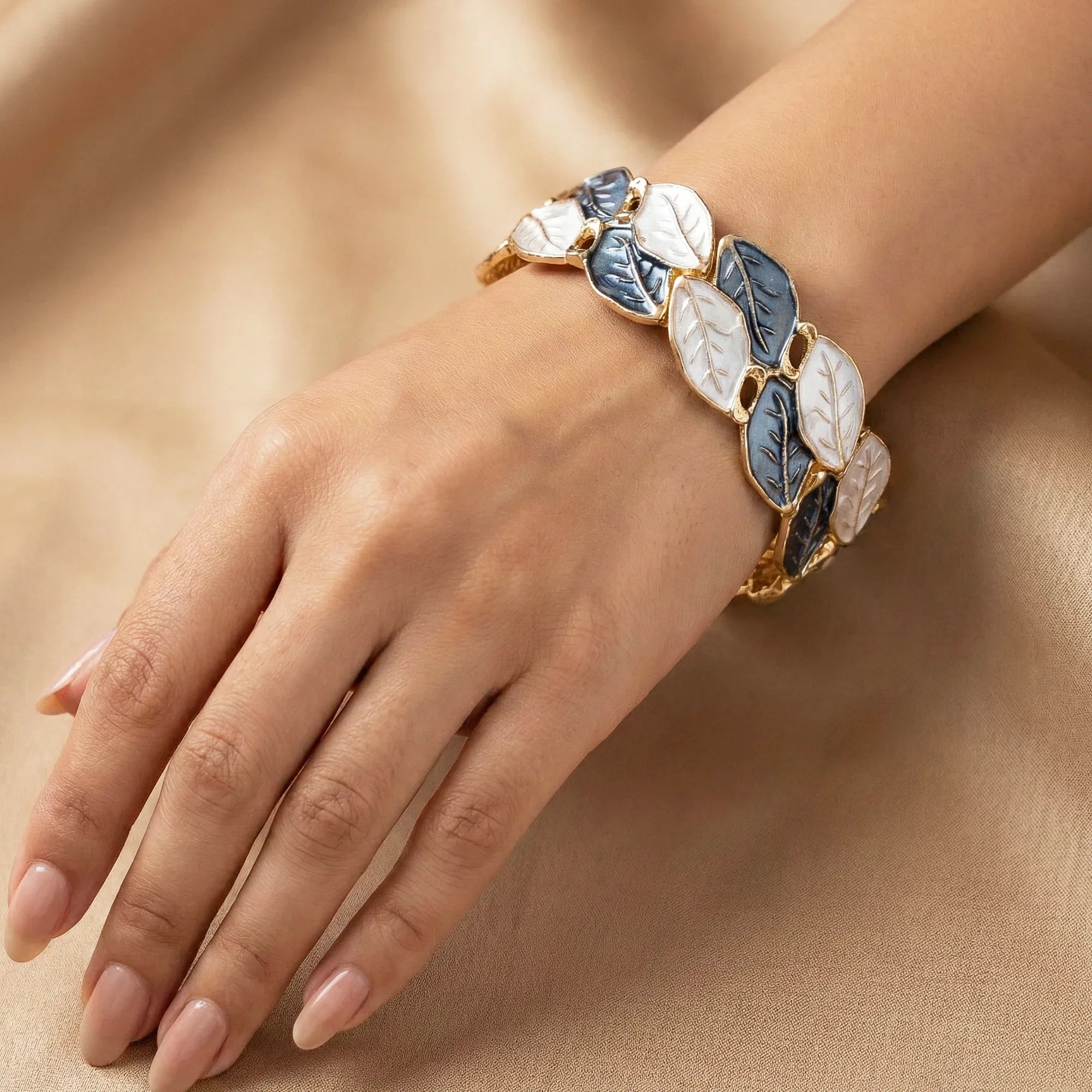 Bracelet with leaf design on a hand against a beige background