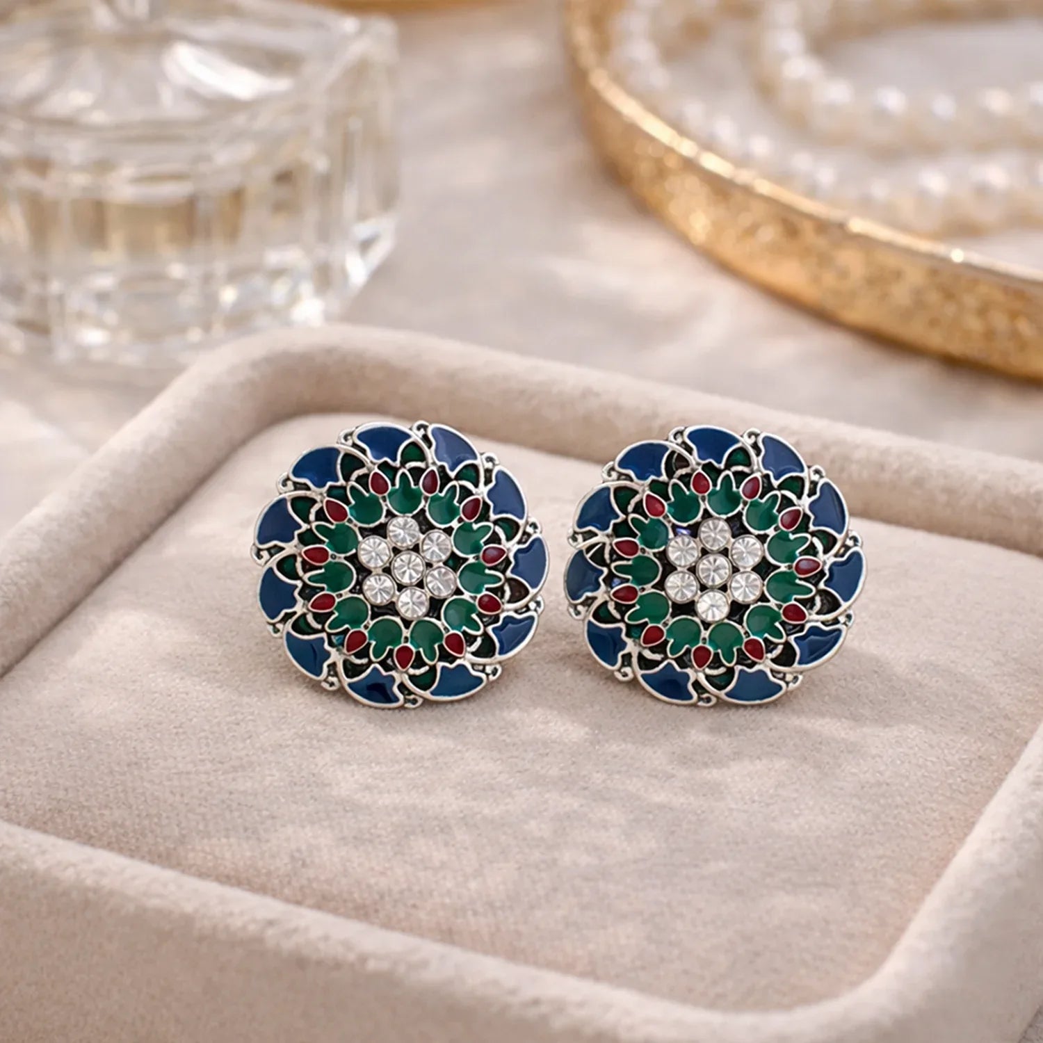 Pair of floral earrings with gemstones on a beige jewelry box