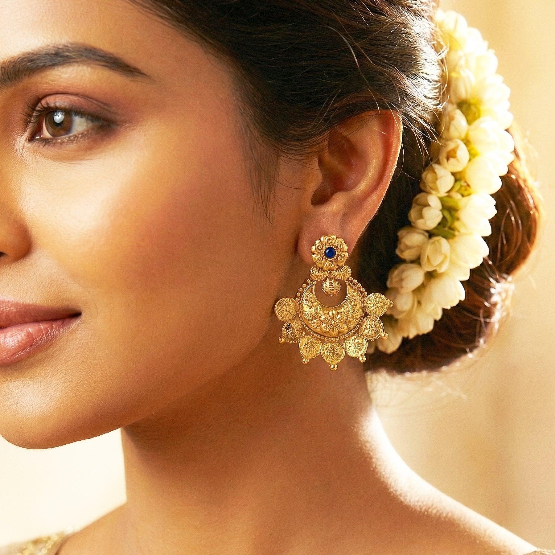 Close-up of a woman wearing gold earrings with a blurred background