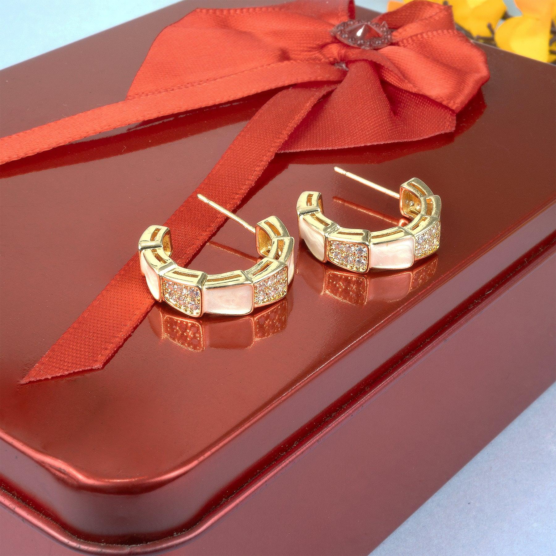 Gold hoop earrings on a red surface with a red ribbon
