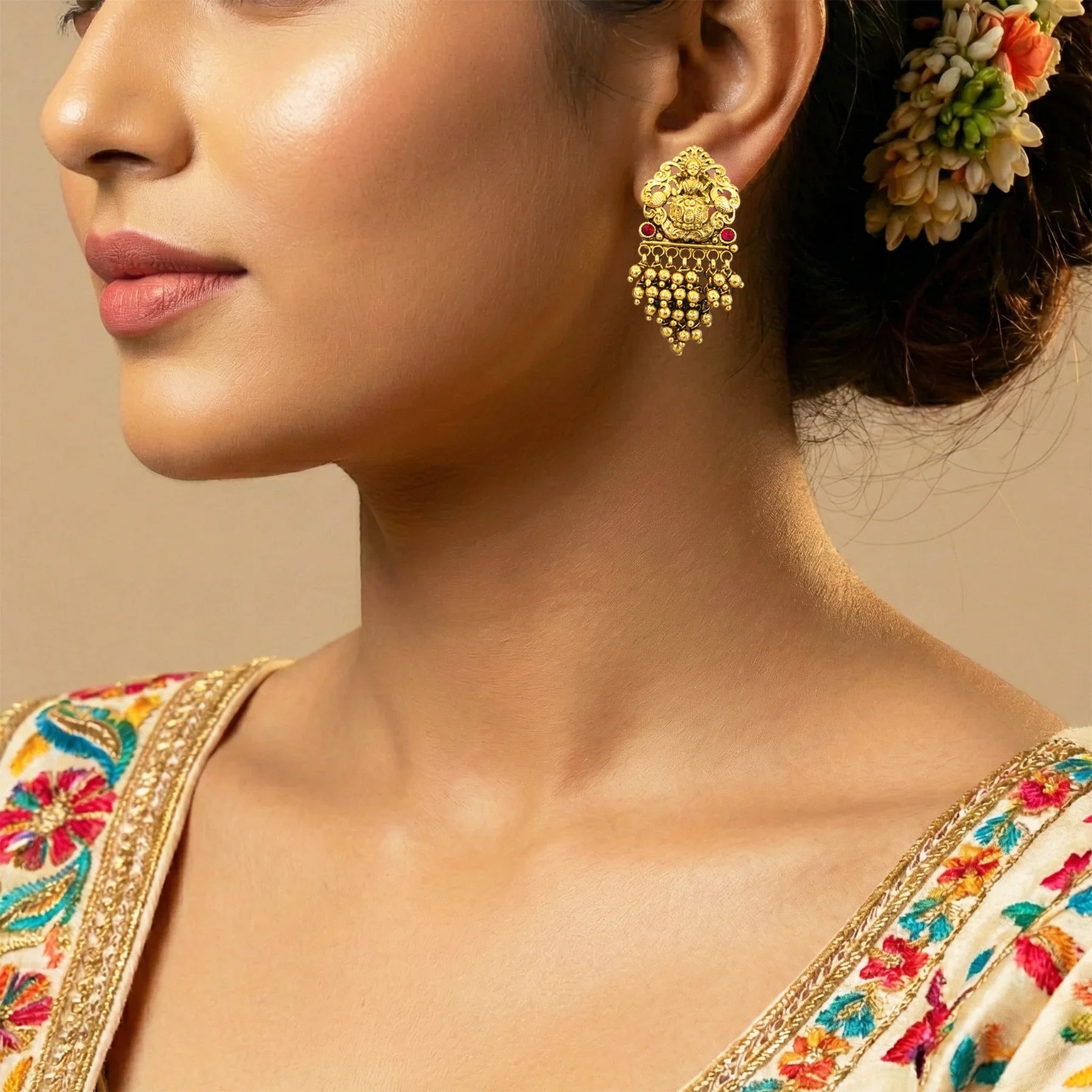 Close-up of a woman wearing gold earrings with a neutral background
