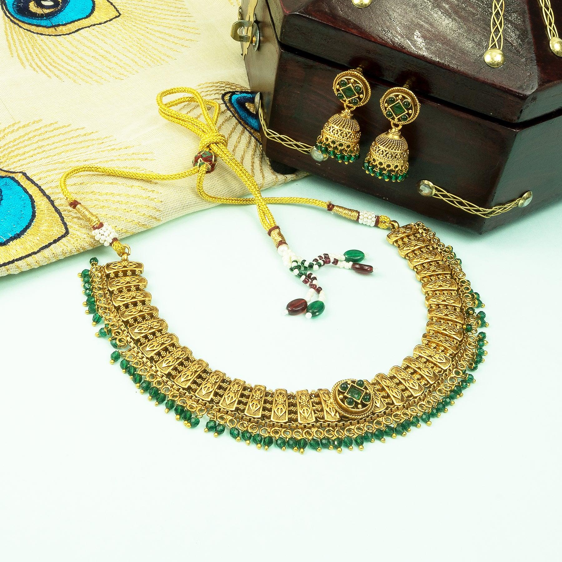 Gold necklace with green beads and matching earrings on a white background