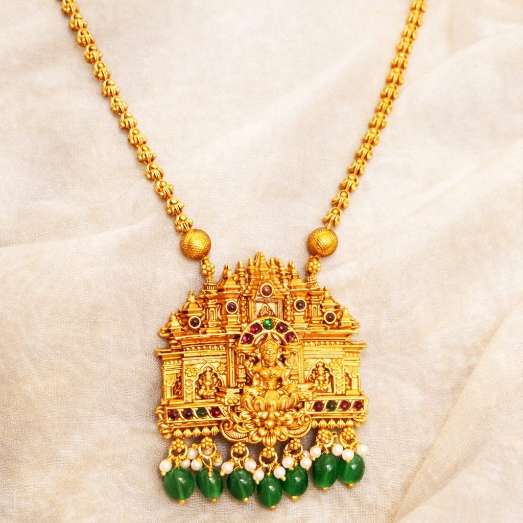 Gold necklace with intricate pendant on a beige background