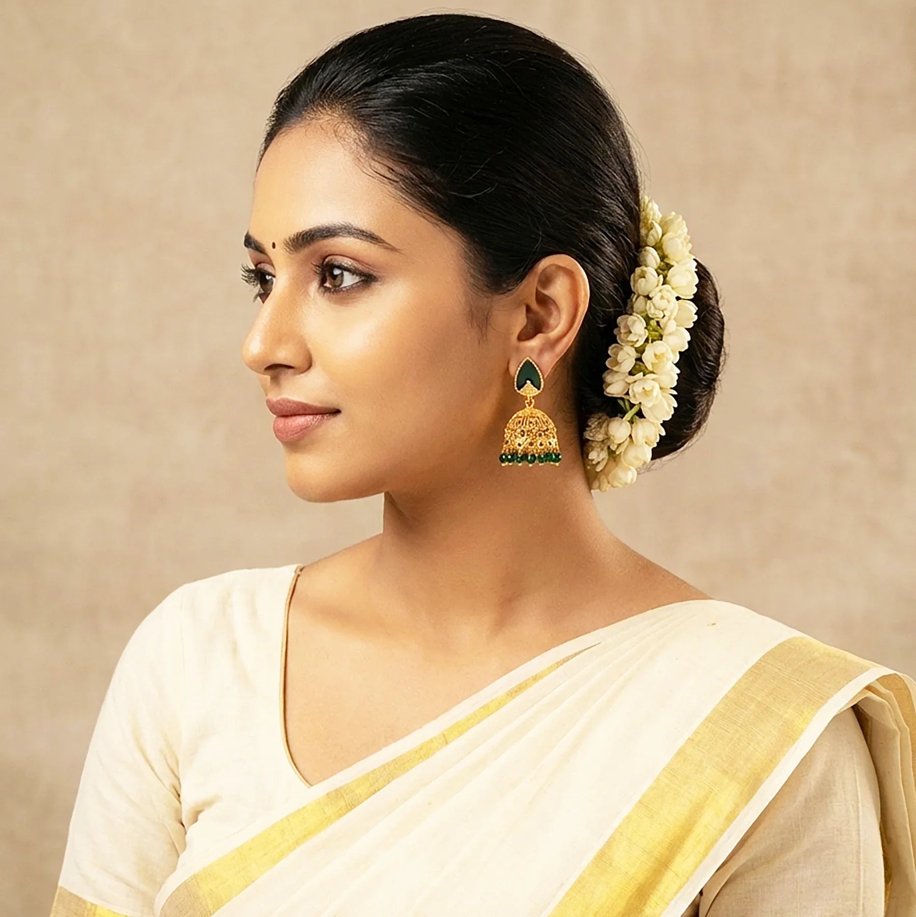 Woman wearing a white saree with gold border and floral hair accessory against a beige background
