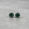 Pair of silver earrings with green gemstones on a gray background