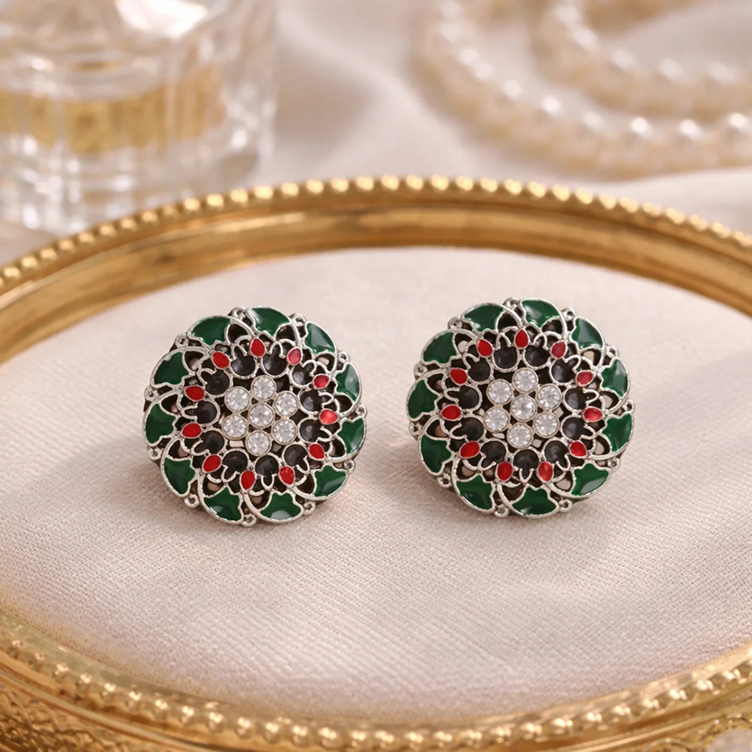 Decorative earrings with green, red, and black design on a gold and white background
