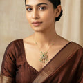Woman wearing a brown saree with a decorative necklace against a beige background