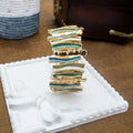 Gold and green jewelry piece on a white stand with a brown background