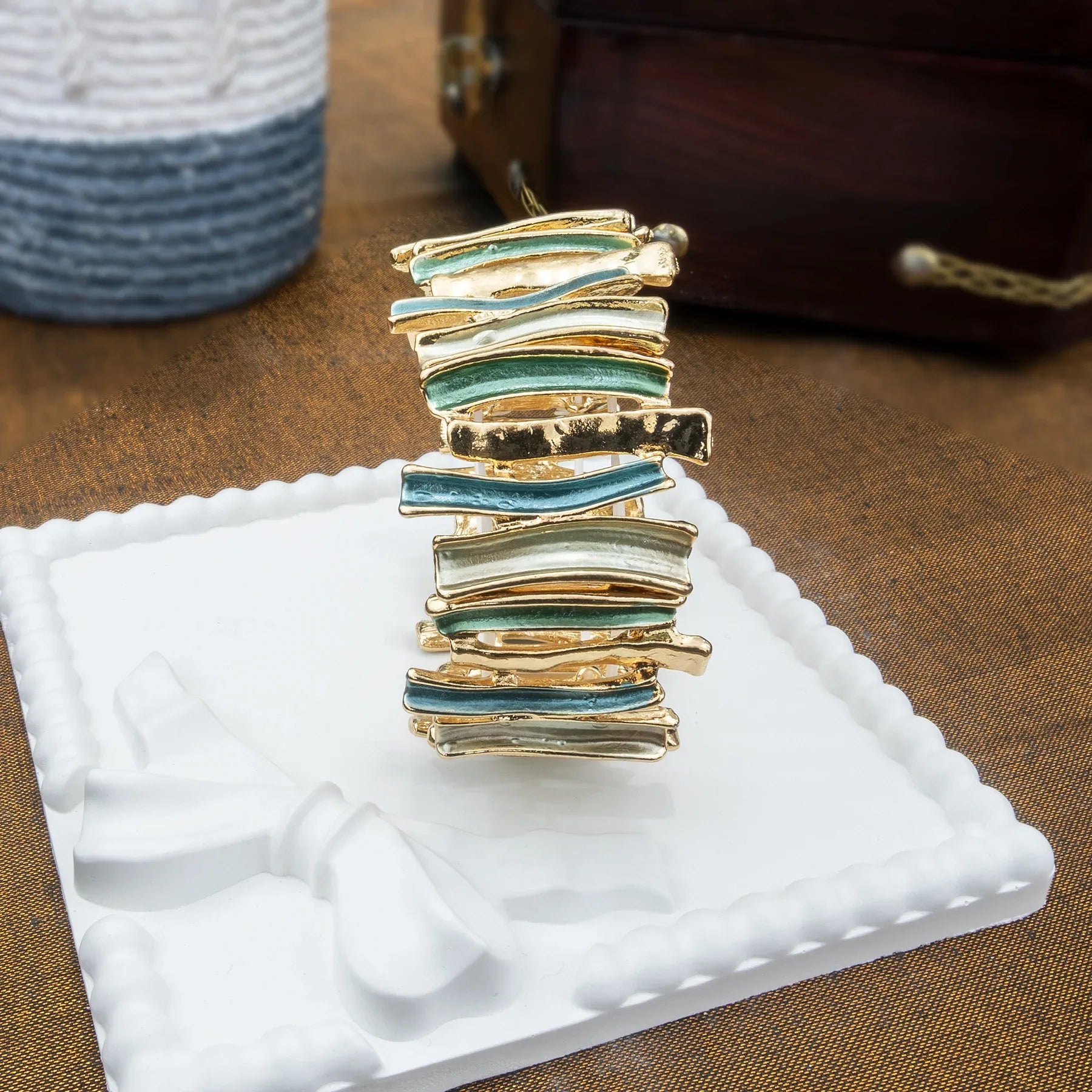 Gold and green jewelry piece on a white stand with a brown background