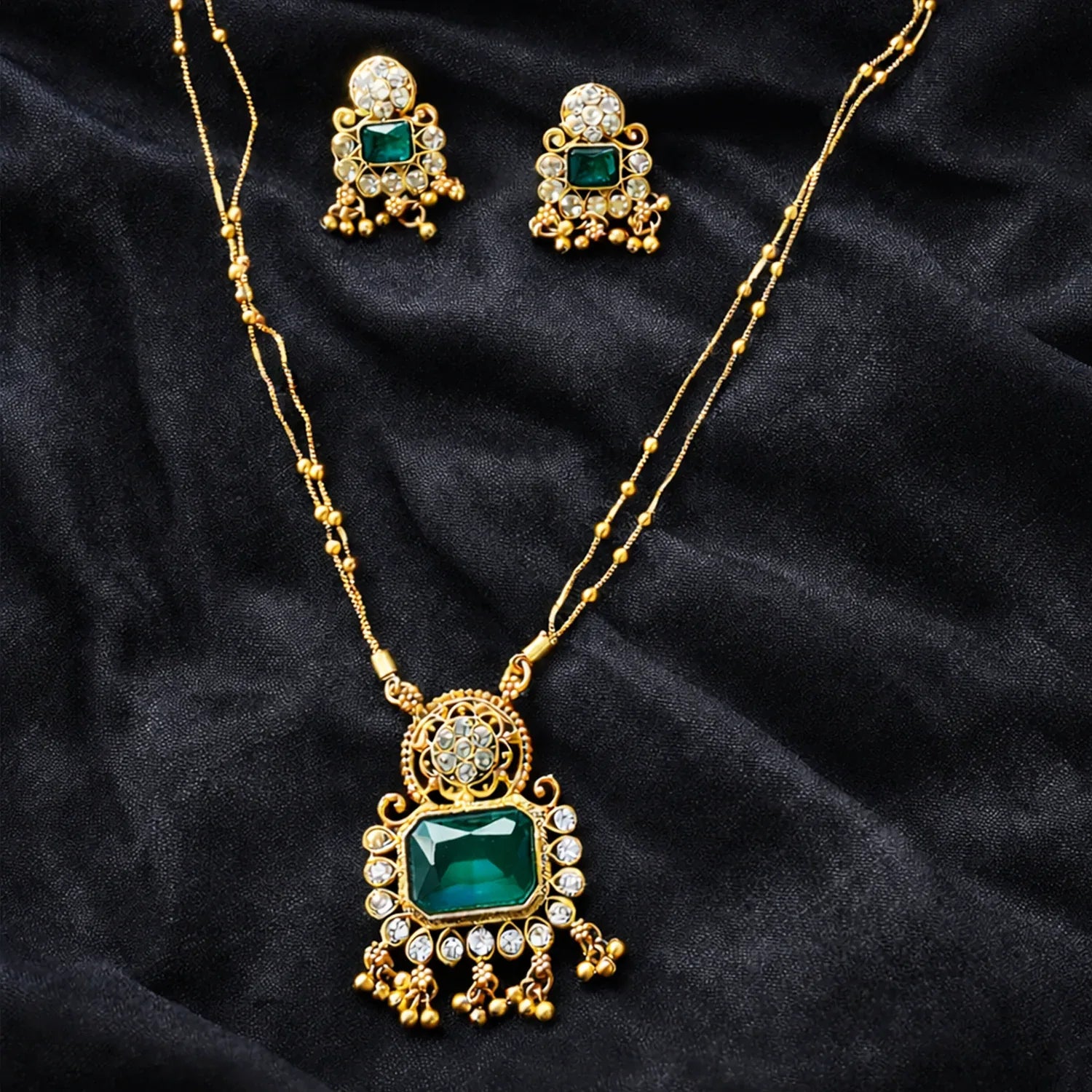 Gold necklace with green gemstones on a black fabric background