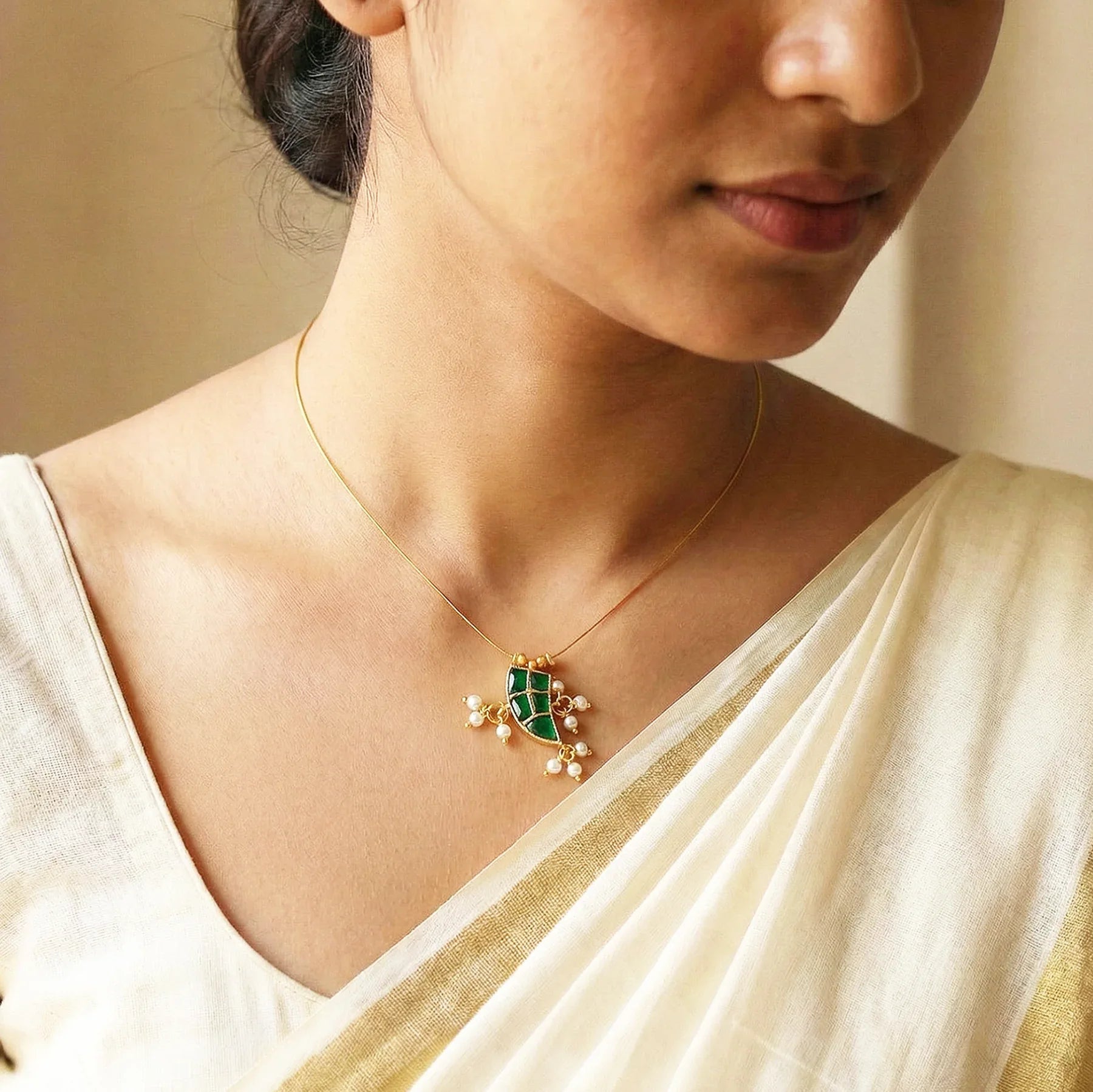 Woman wearing a gold necklace with a green pendant