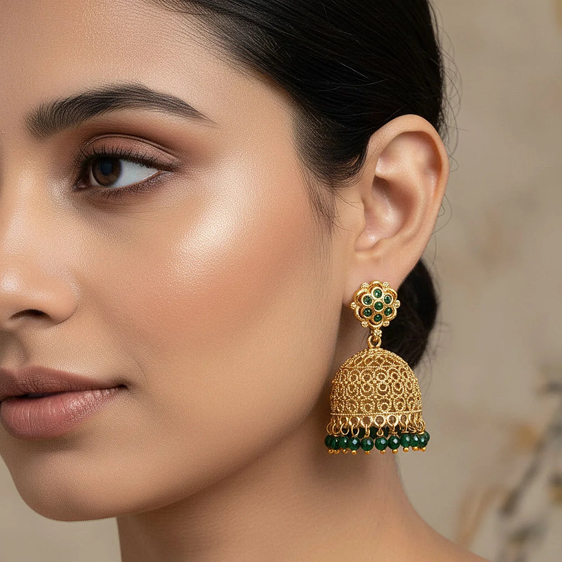 Close-up of a woman wearing a gold and green earring with a blurred background