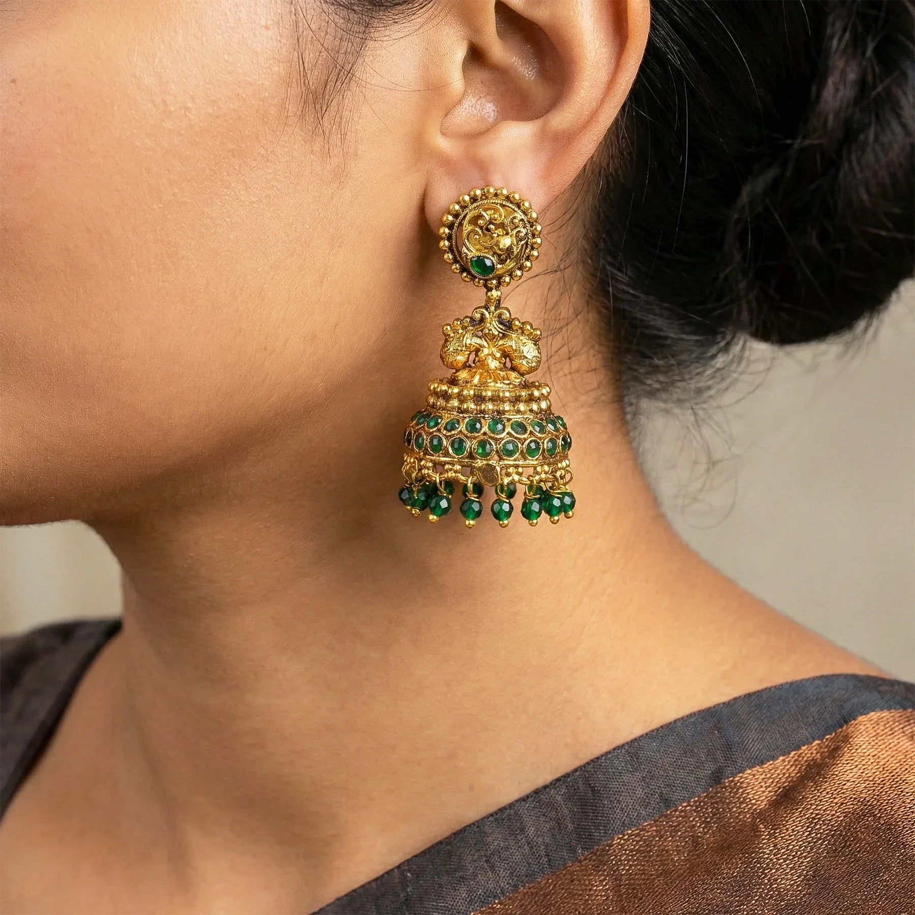 Gold and green earrings worn by a person