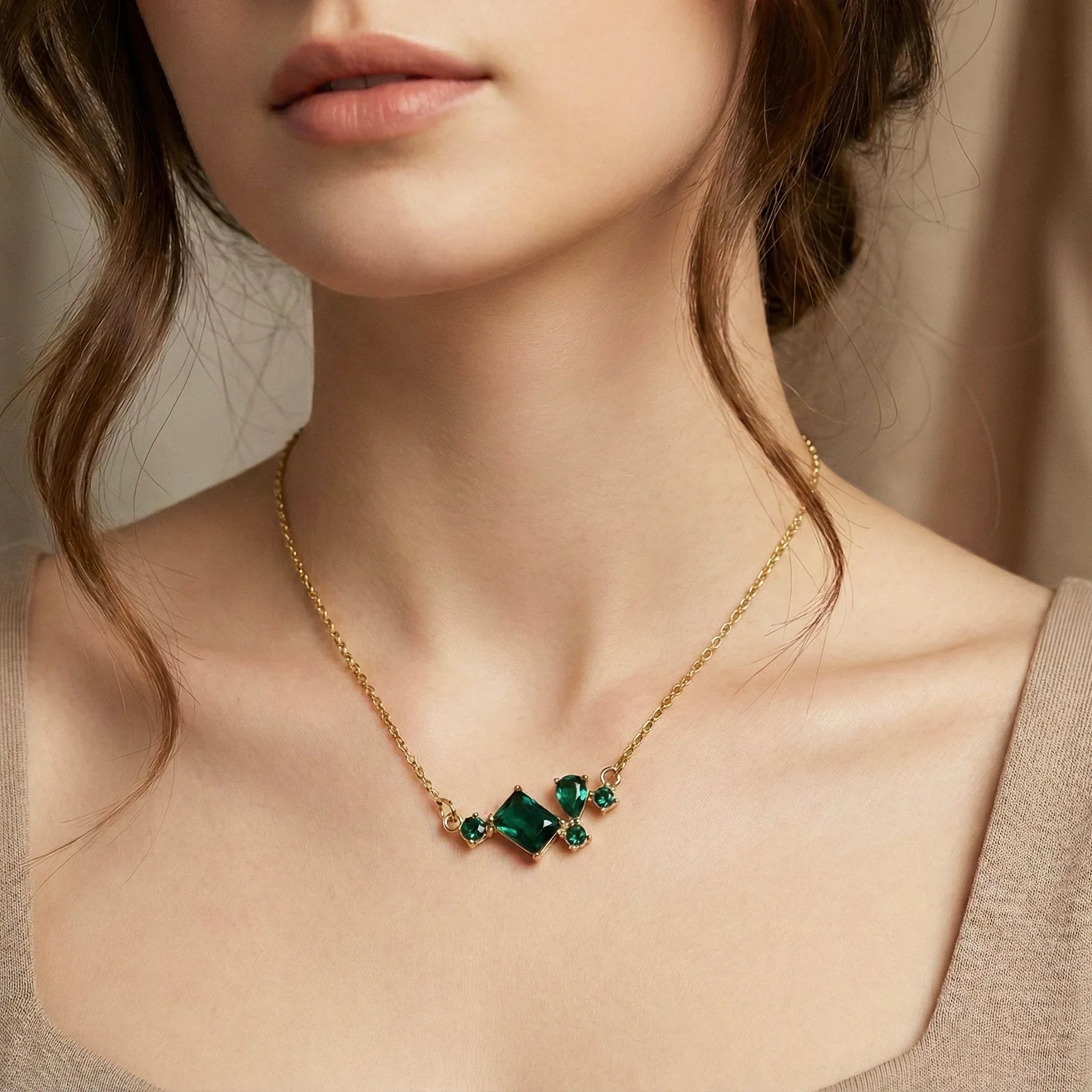 Gold necklace with green gemstones worn by a person