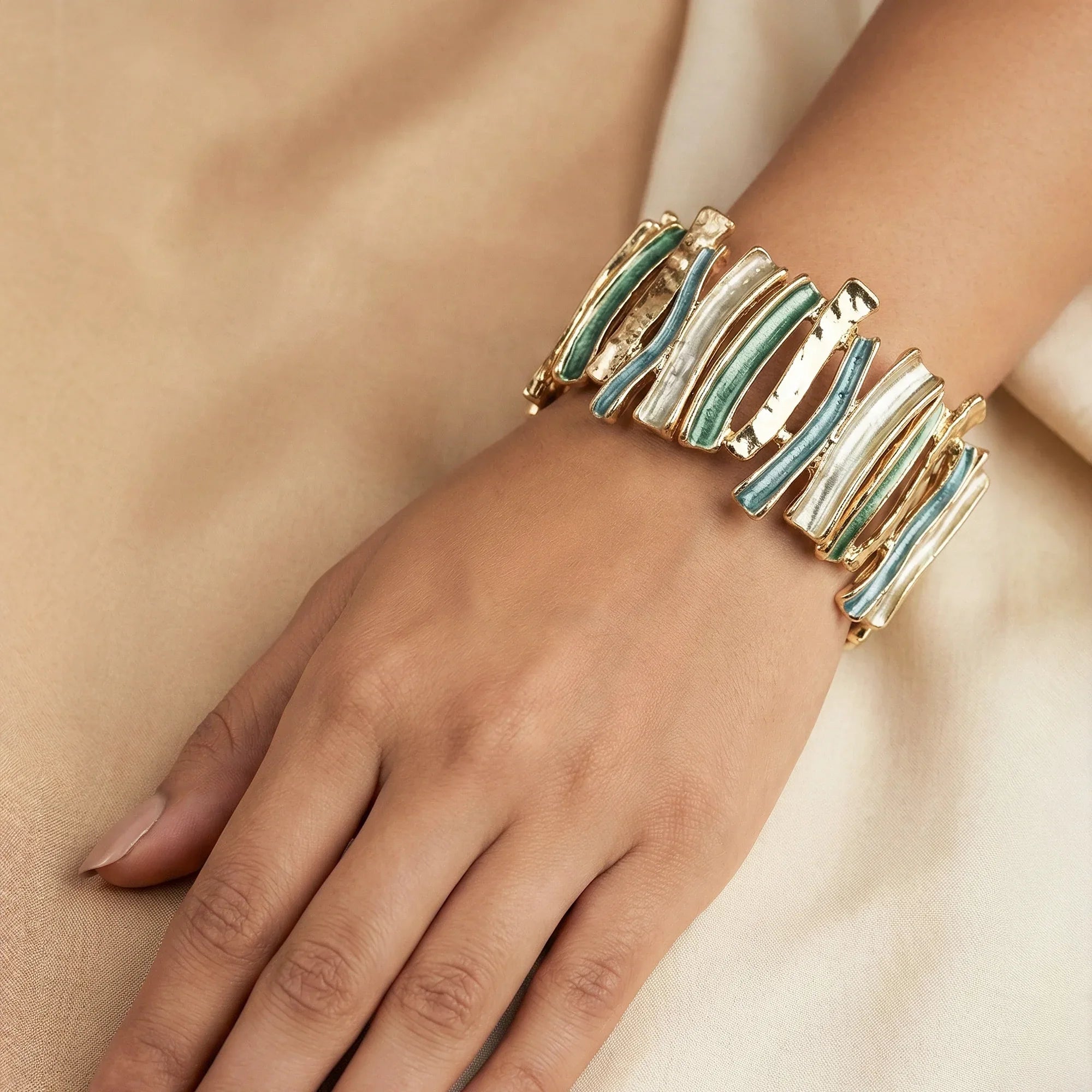 Gold and turquoise bracelet on a hand against a neutral background