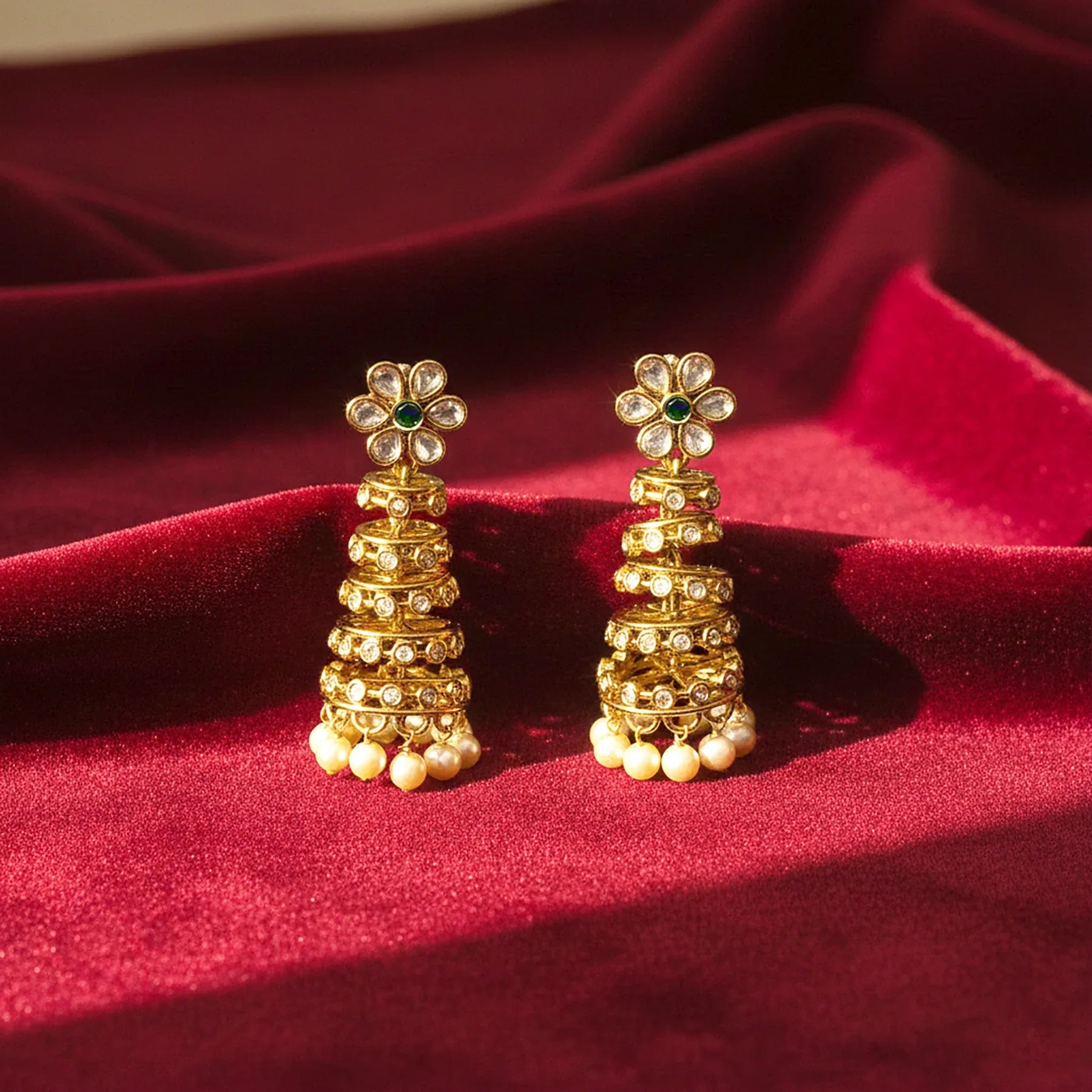 Gold earrings with floral designs on a red fabric background