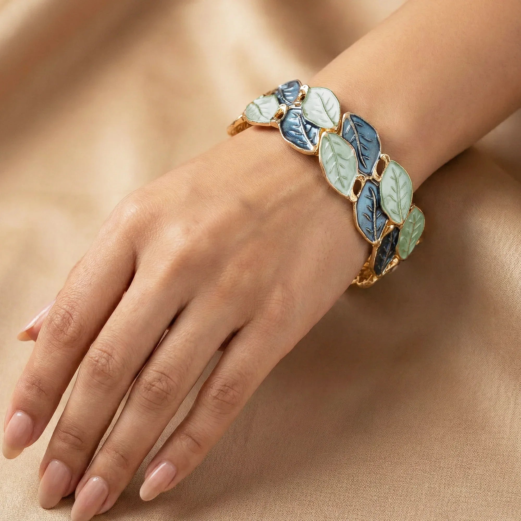 Bracelet with leaf design on a hand against a beige background