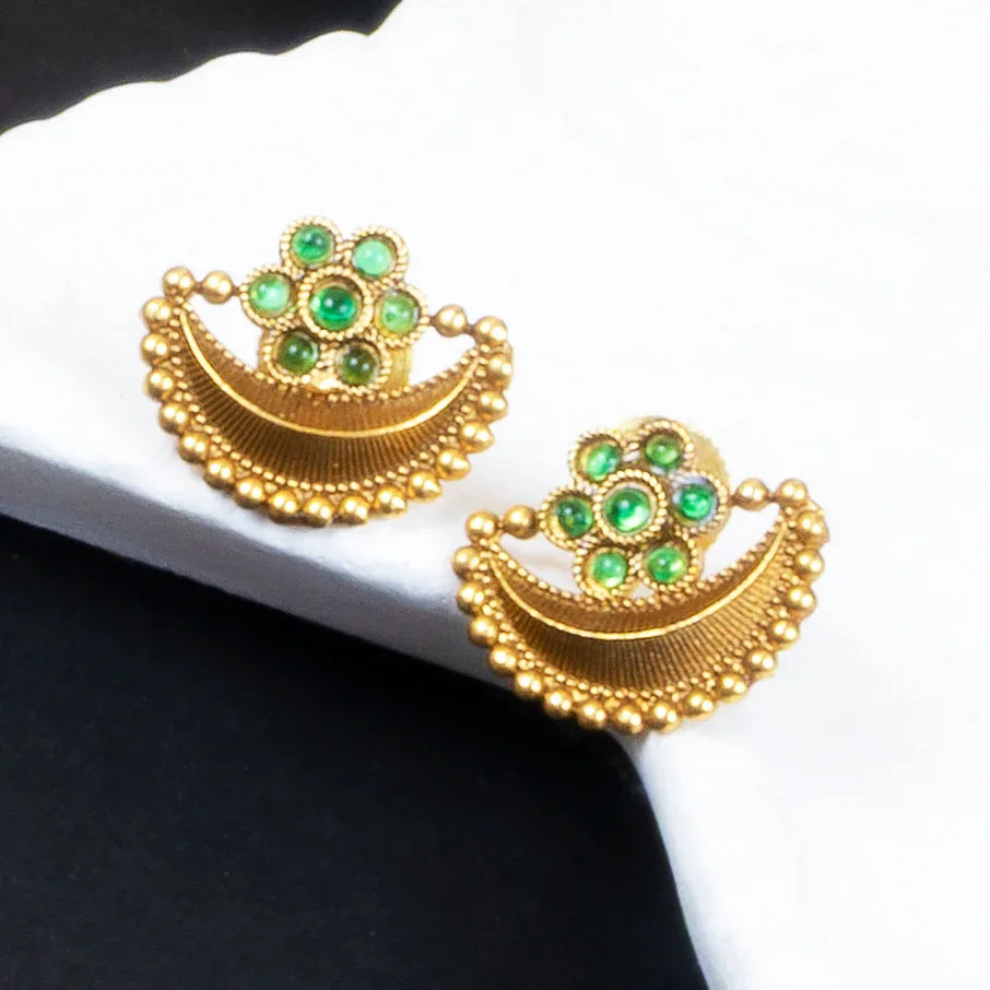 Gold earrings with green gemstones on a white surface