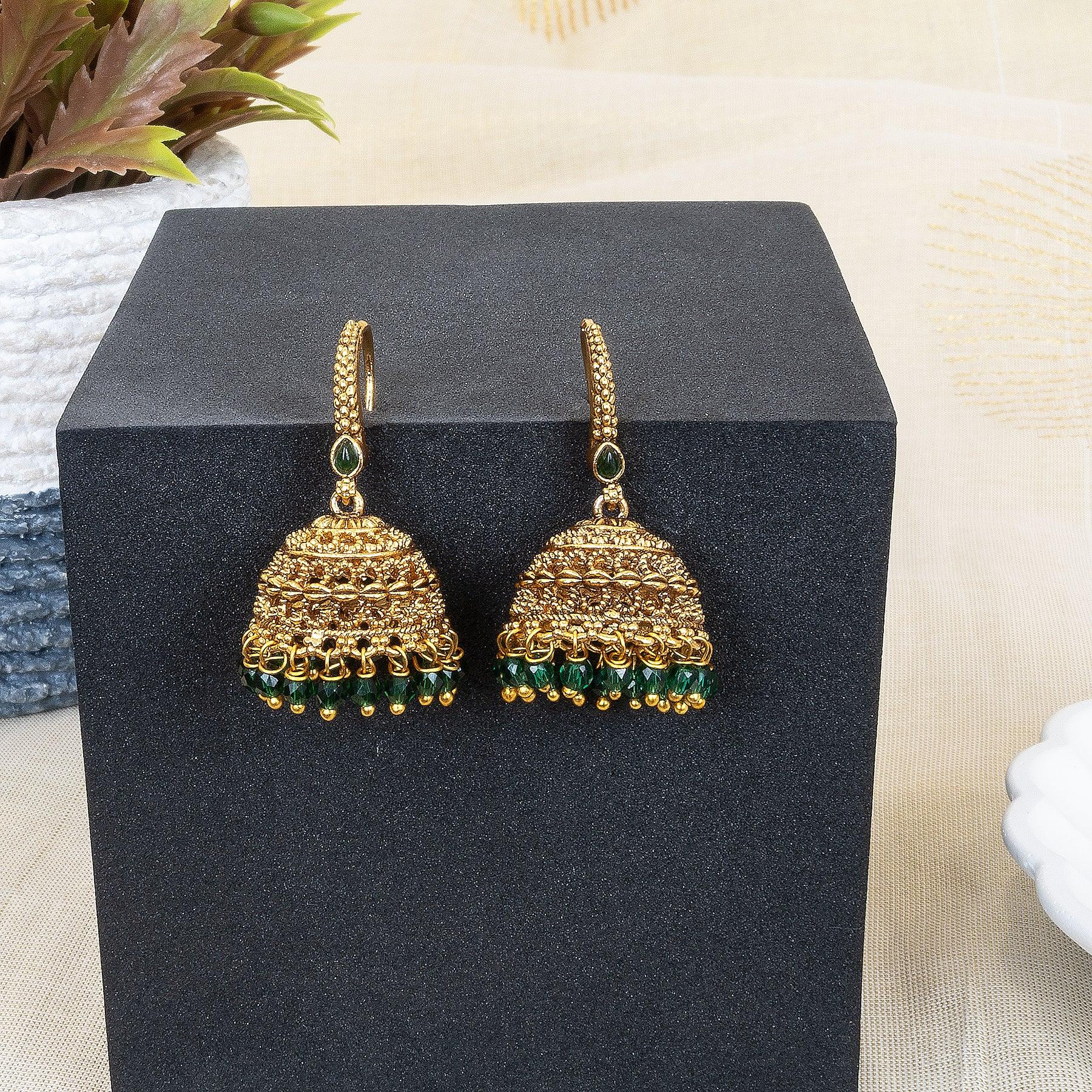 Gold and green earrings on a black stand with a neutral background
