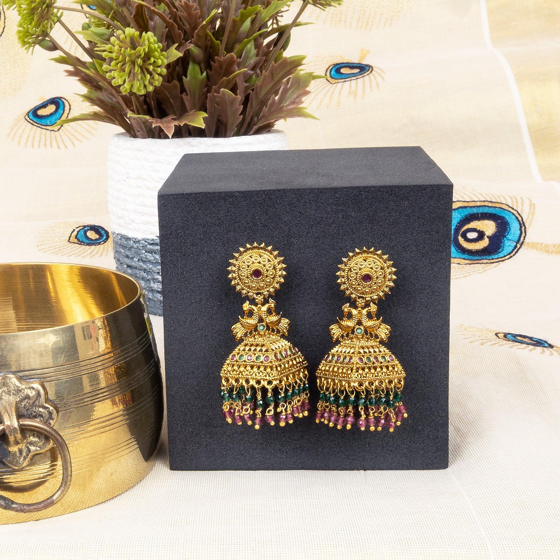 Gold earrings on a black box with decorative elements in the background