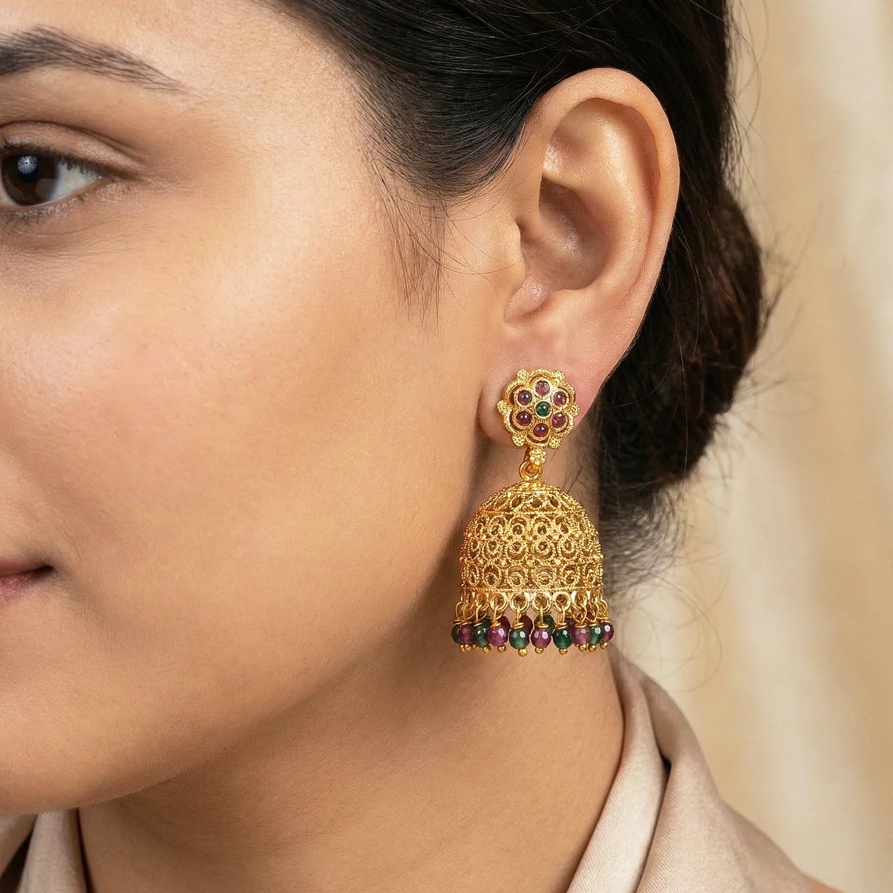 Close-up of a woman wearing a gold earring with colorful beads.