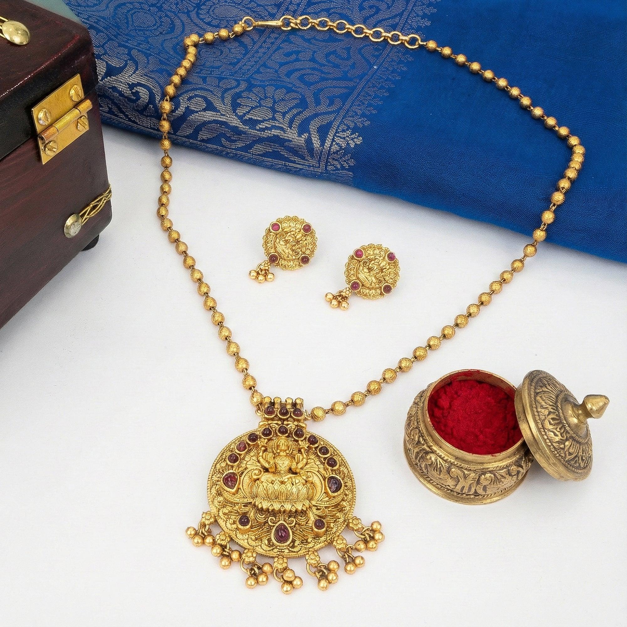 Gold necklace with pendant, earrings, and decorative box on a white background