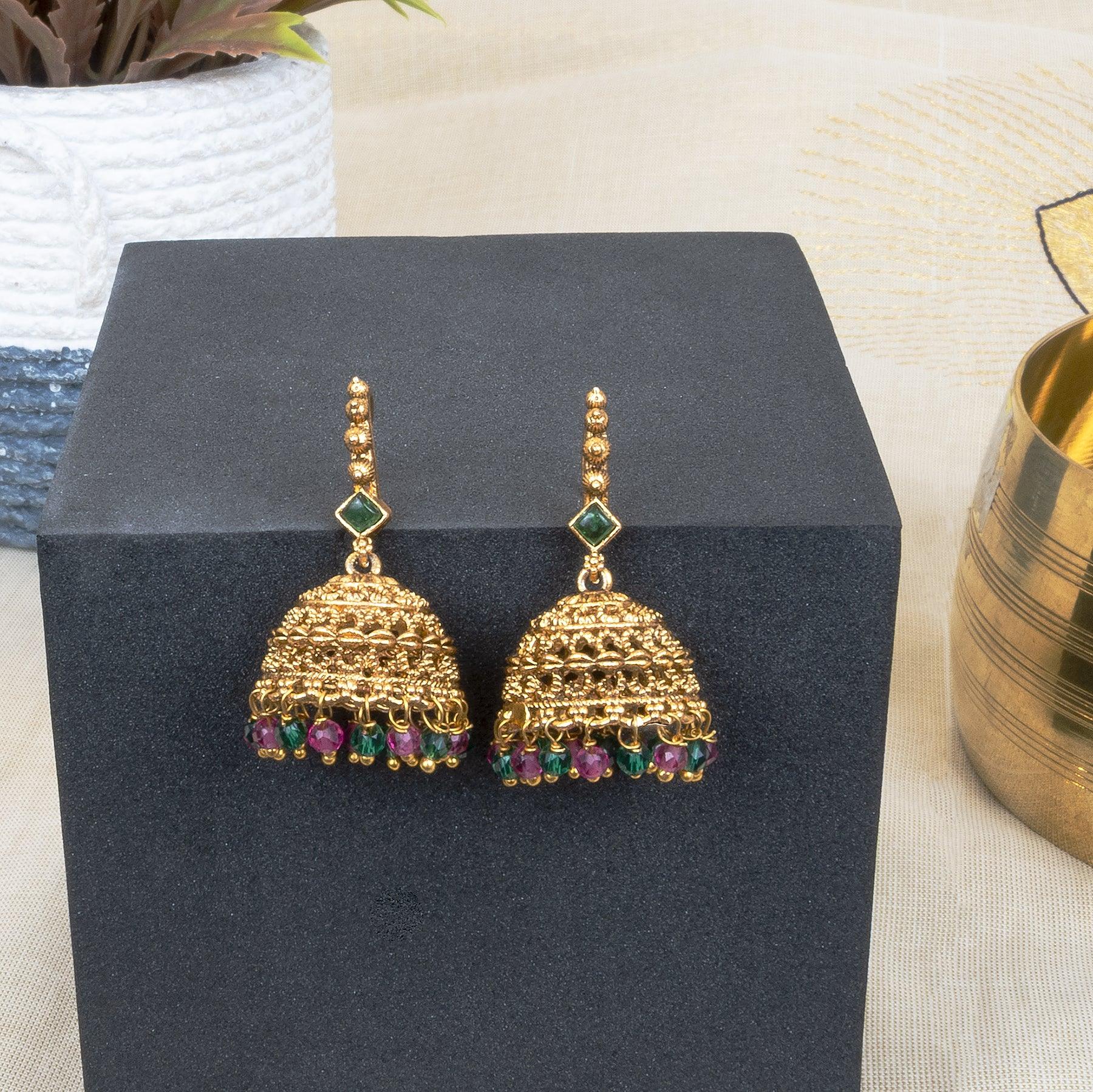 Gold earrings with gemstones on a black stand