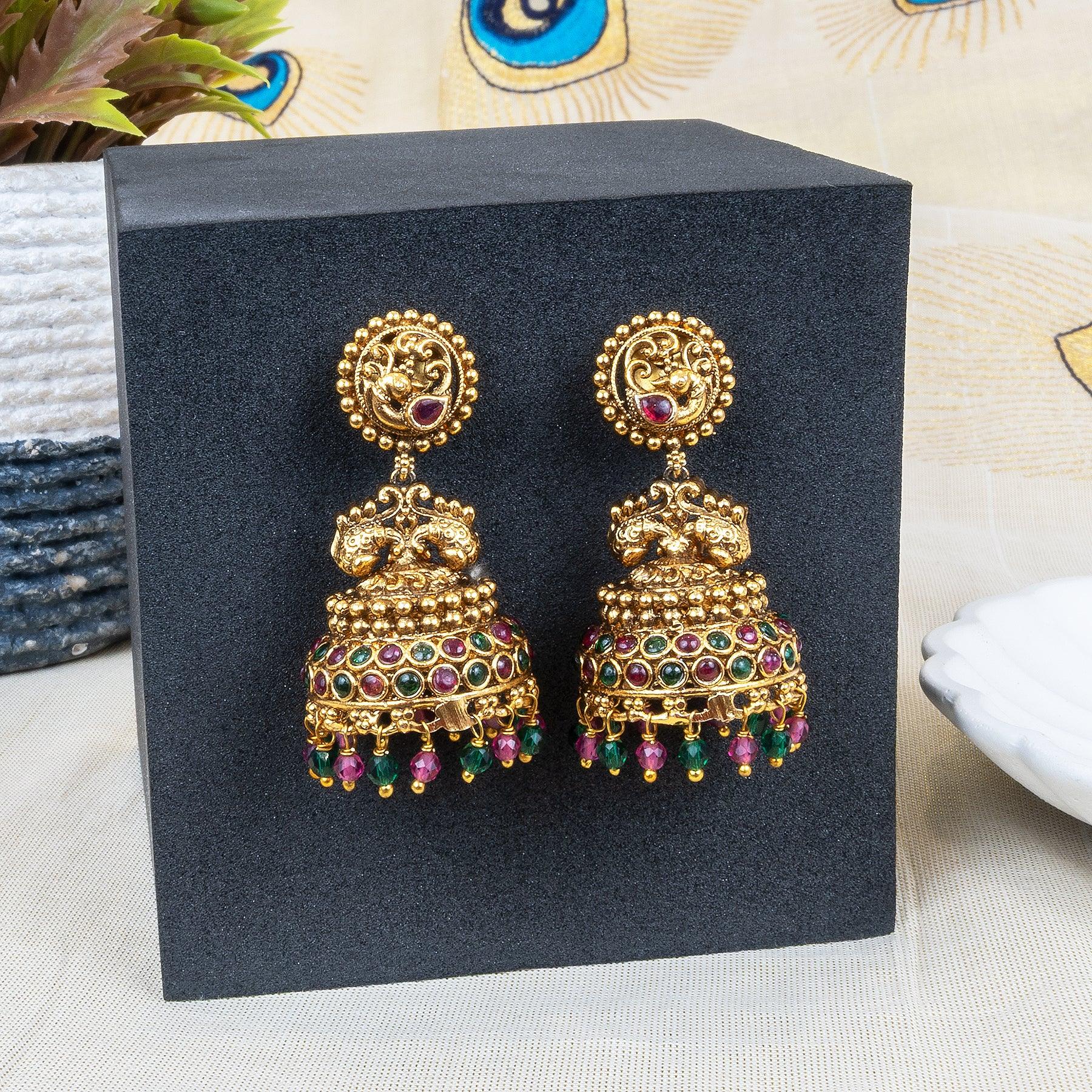 Gold earrings with colorful gemstones on a black stand