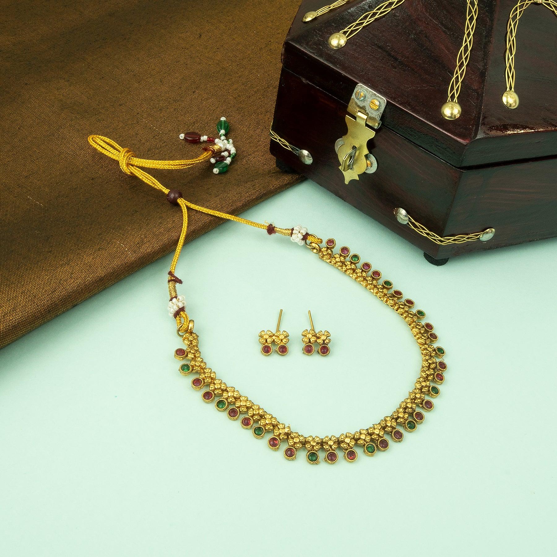 Jewelry set including a necklace, earrings, and bracelet on a green surface with a wooden box.