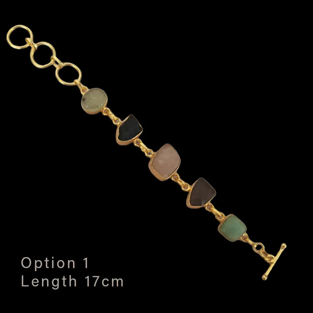 Gold bracelet with colored stones on a black background